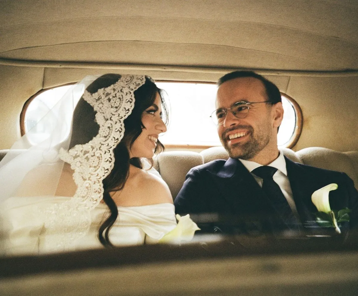 Newlyweds laughing in the back of a vintage car, on 35mm film