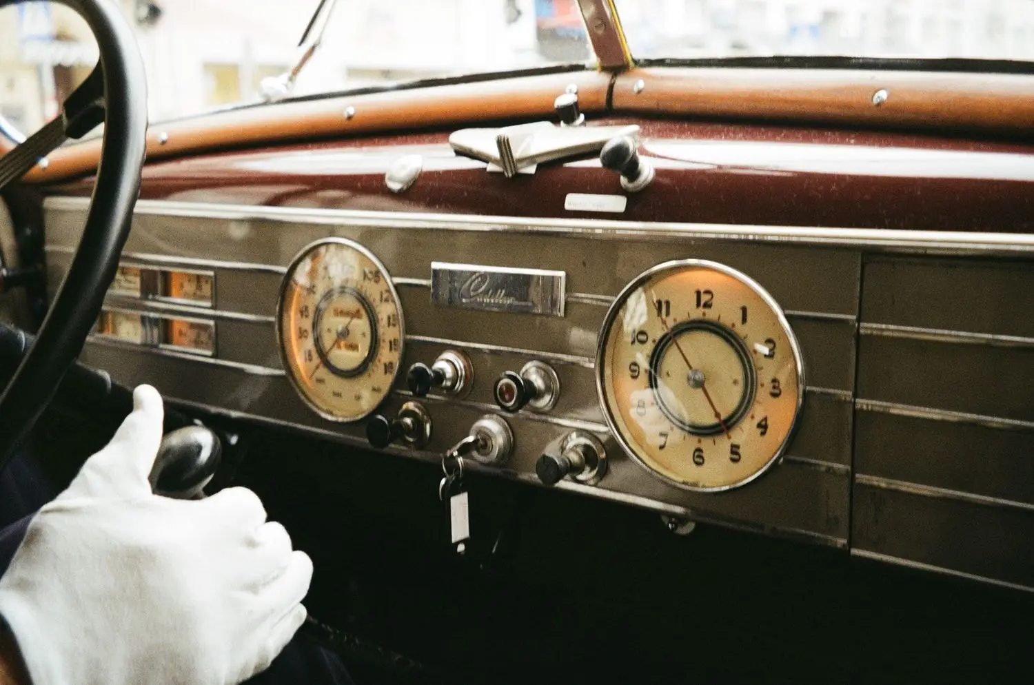 Chauffeur's gloved hand on a vintage car dashboard, on 35mm film