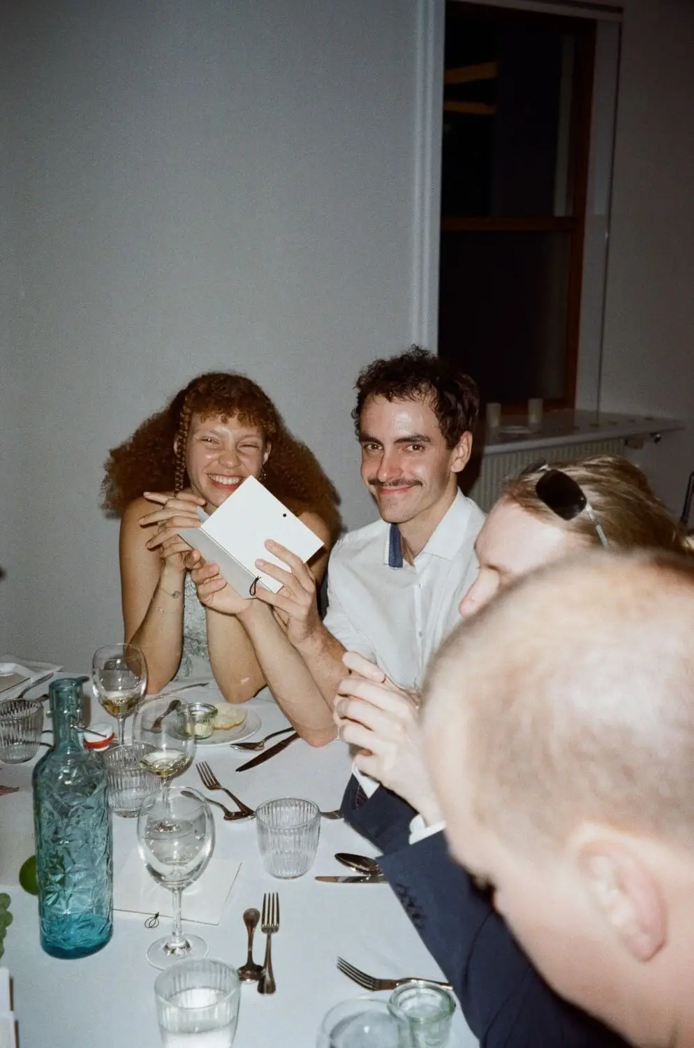 Guests reading cards and laughing at the dinner table, on 35mm film
