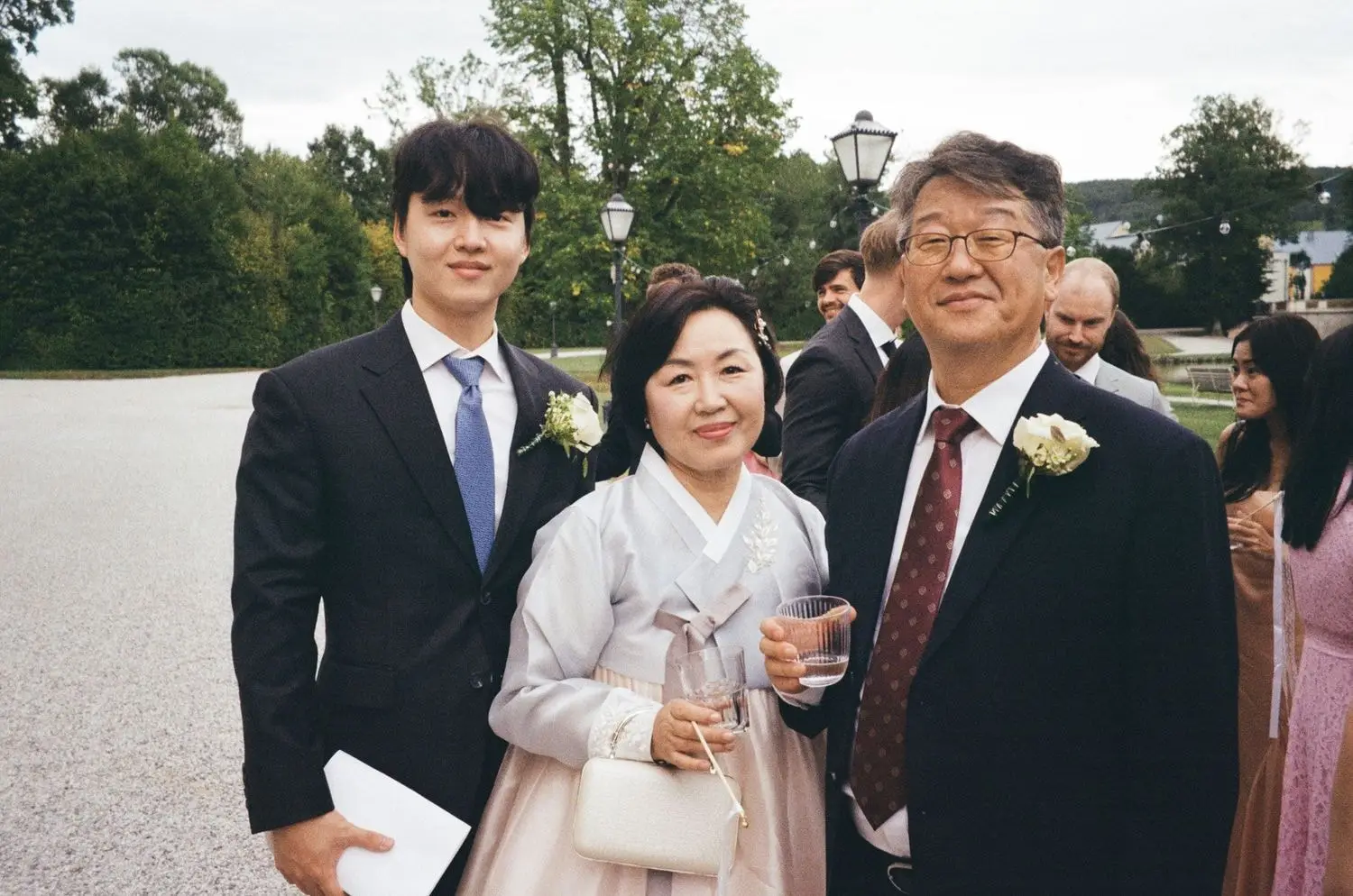 Family of the bride and groom in suits and hanbok in the castle park, on 35mm film
