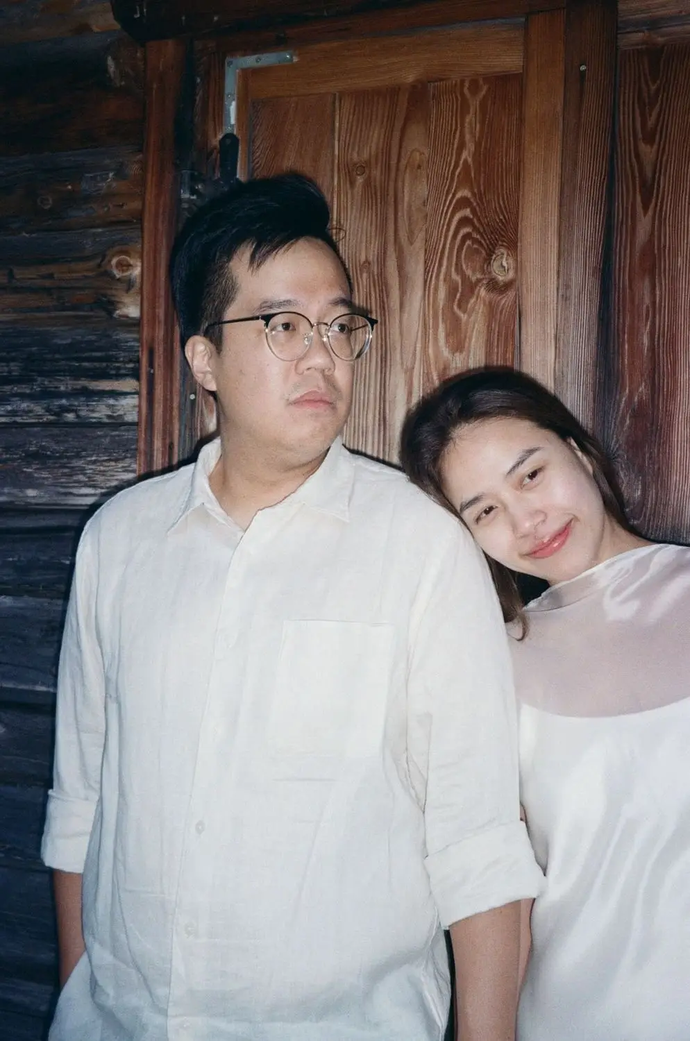 Couple sitting together on the steps of a wooden hut, on 35mm film