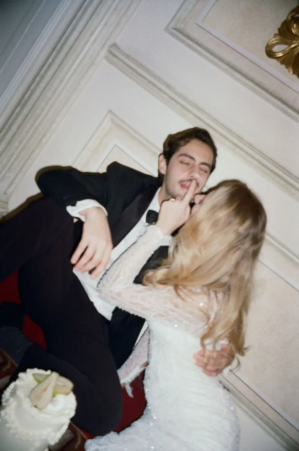 Bride kissing the groom's cheek on a palace sofa, on 35mm film