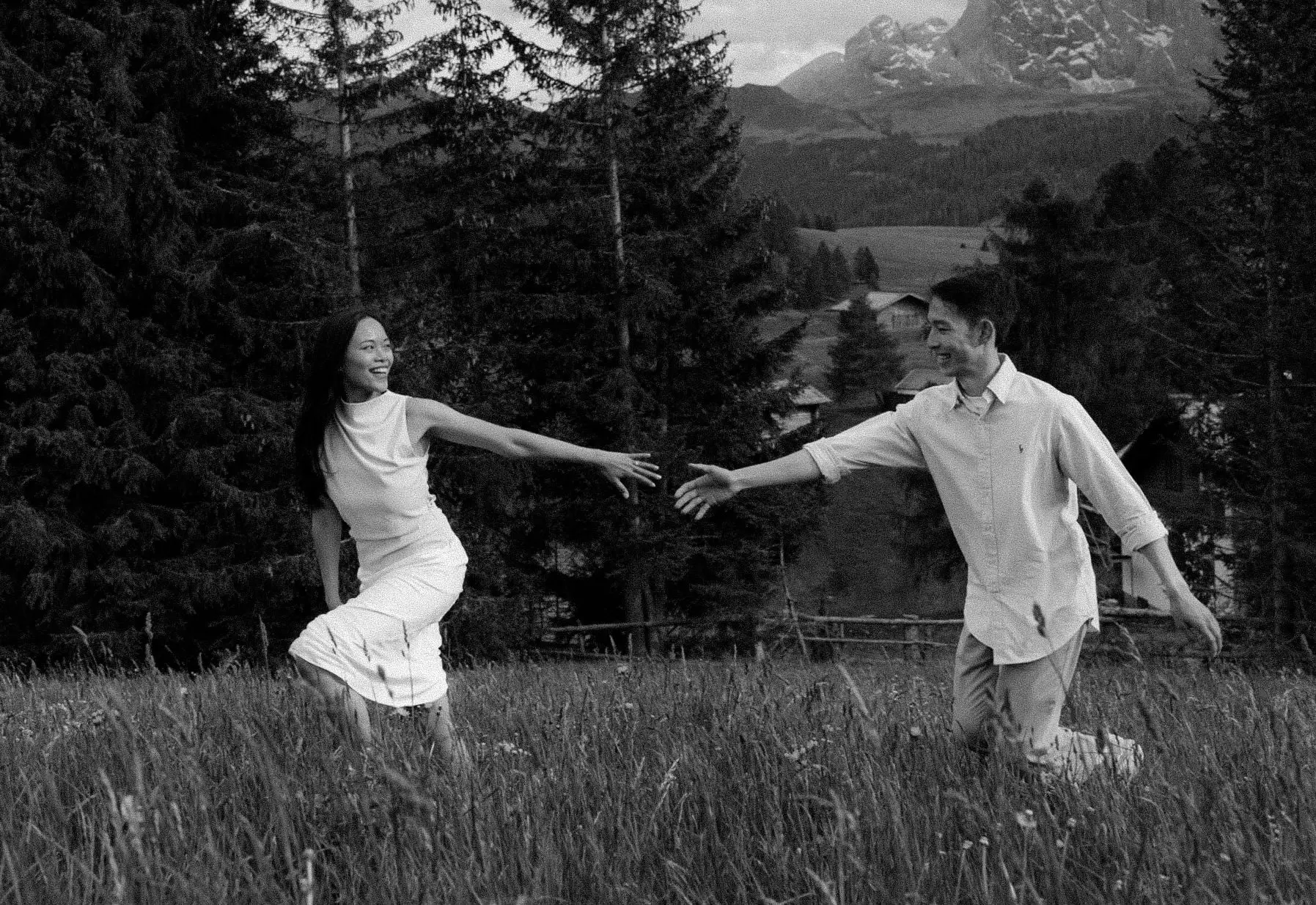 Black and white photo of the couple running hand in hand through the meadow