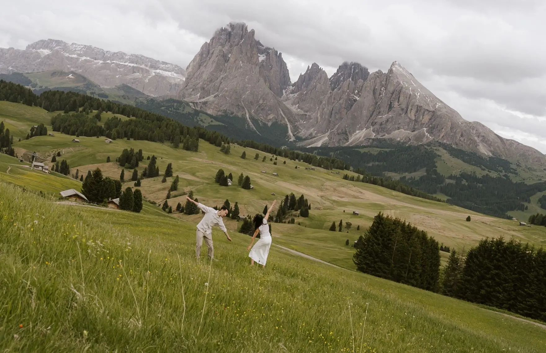 Couple dancing in the rolling meadows of the Alpe di Siusi below the Dolomites