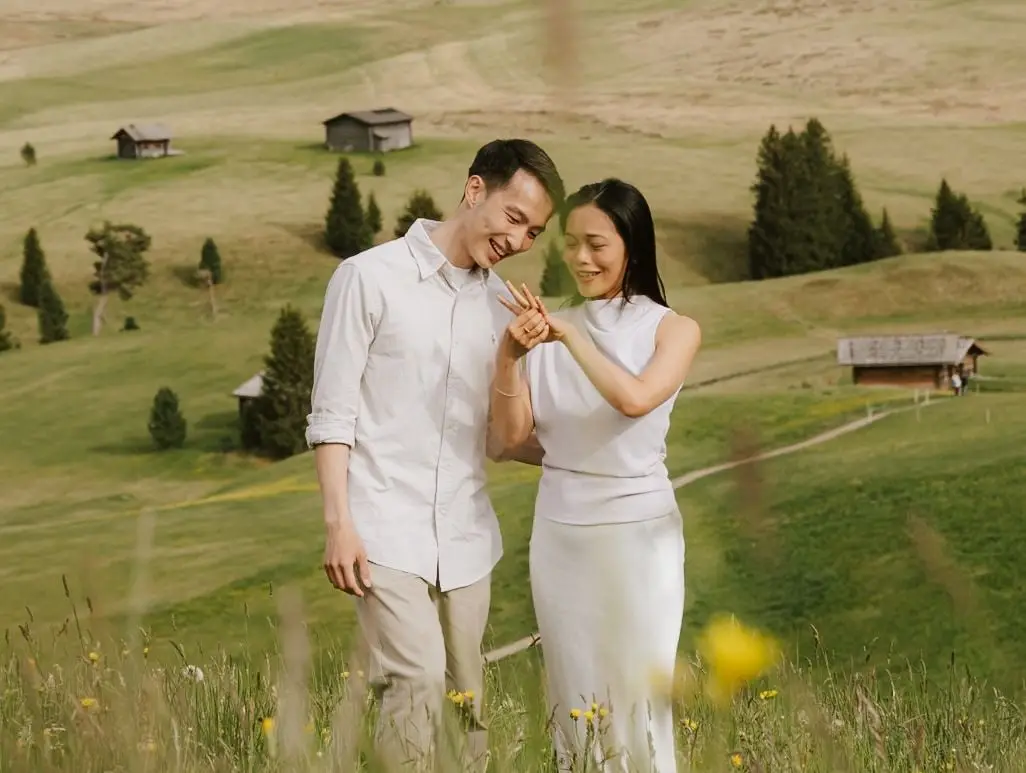 Couple walking and laughing as she looks at her new engagement ring