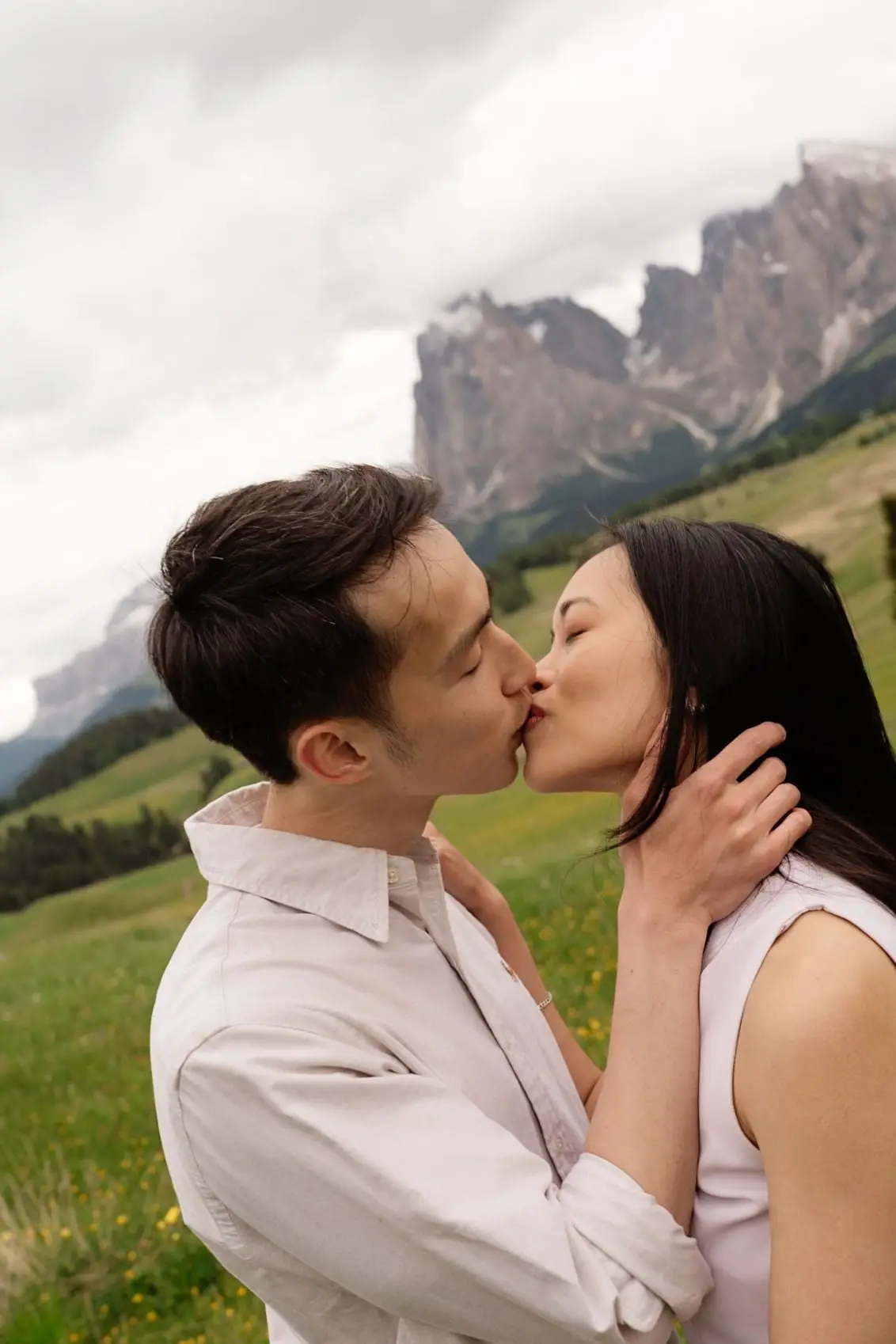 Couple kissing after the proposal with rocky Dolomites peaks behind