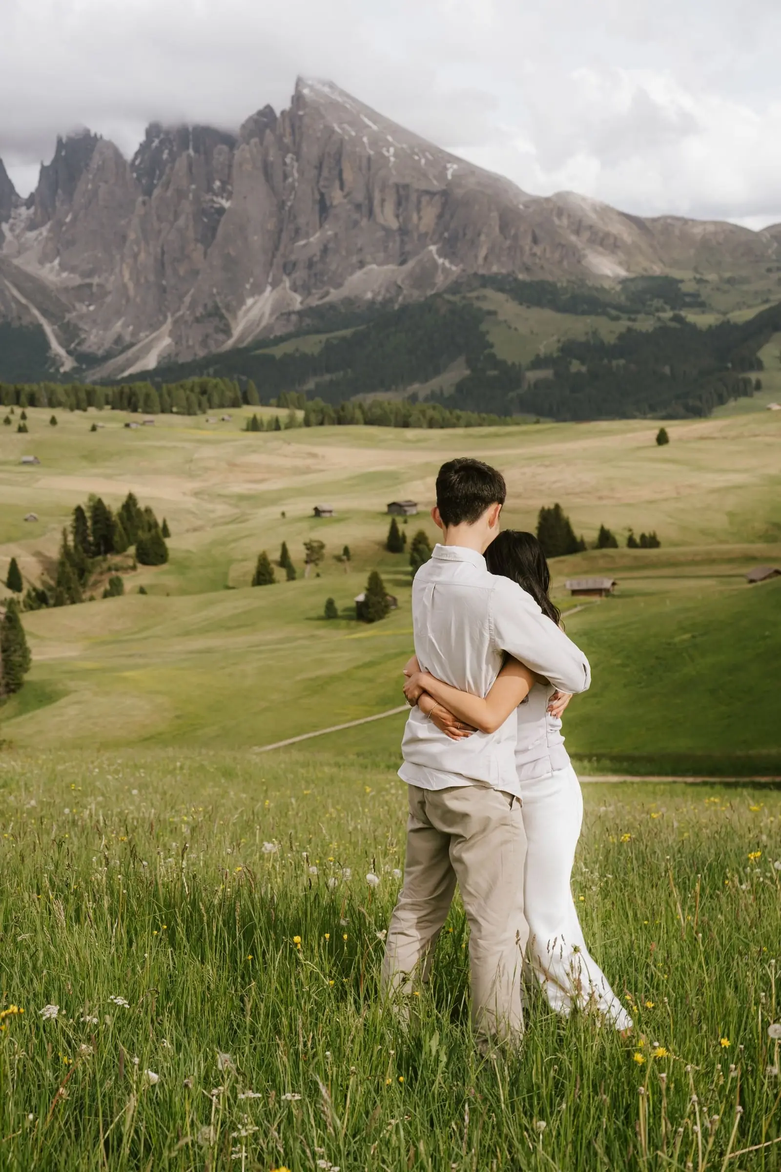 Couple holding each other close in the meadow below the Sassolungo