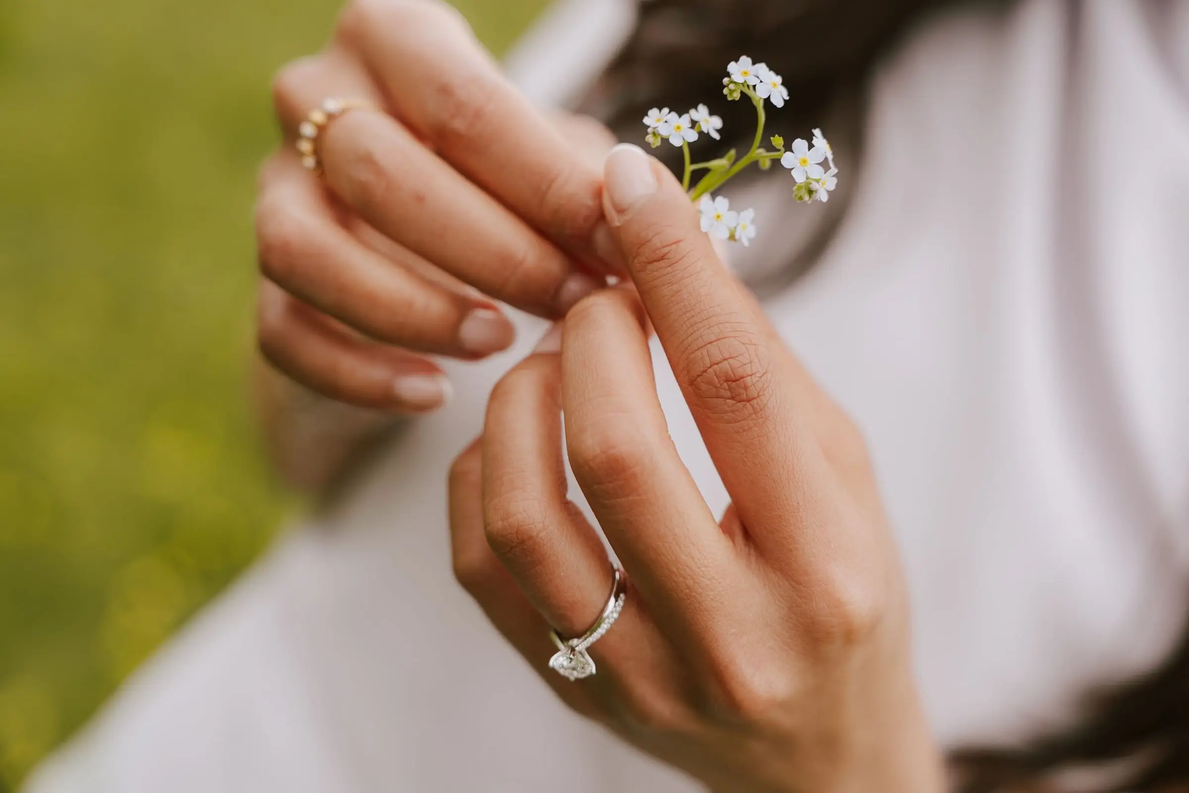 Close-up of her hand with the engagement ring holding a tiny forget-me-not