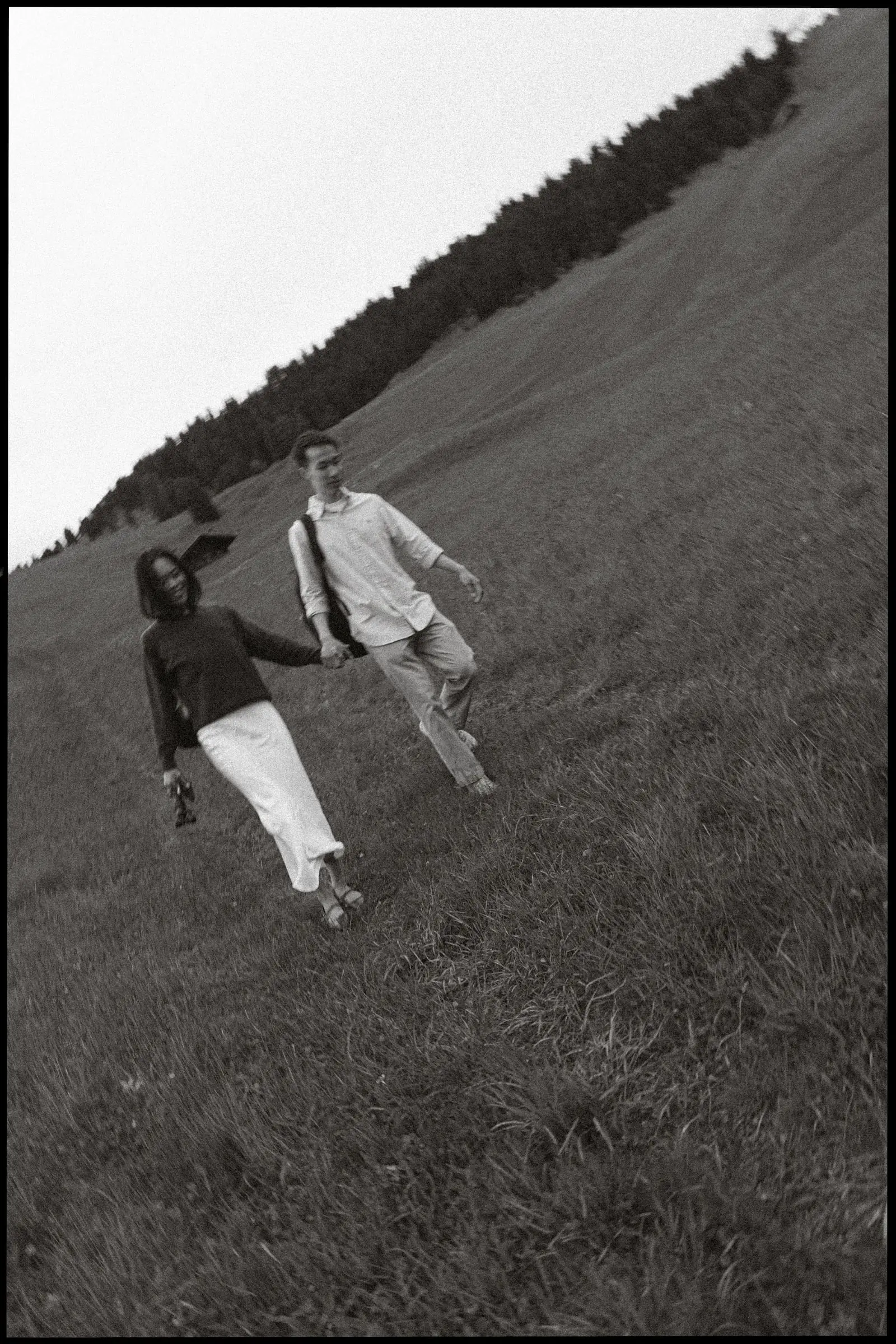 Black and white photo of the couple walking down a steep grassy slope