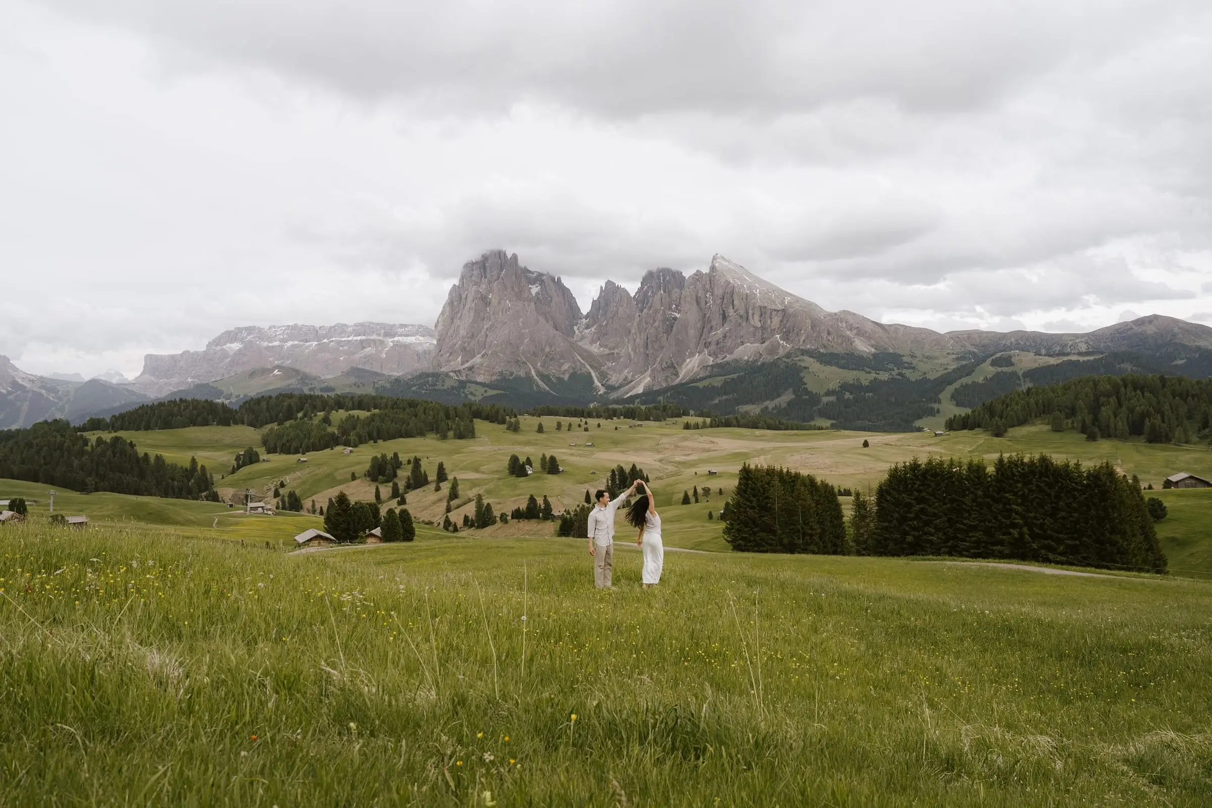 Couple embracing far away in the meadows, the Sassolungo on the horizon