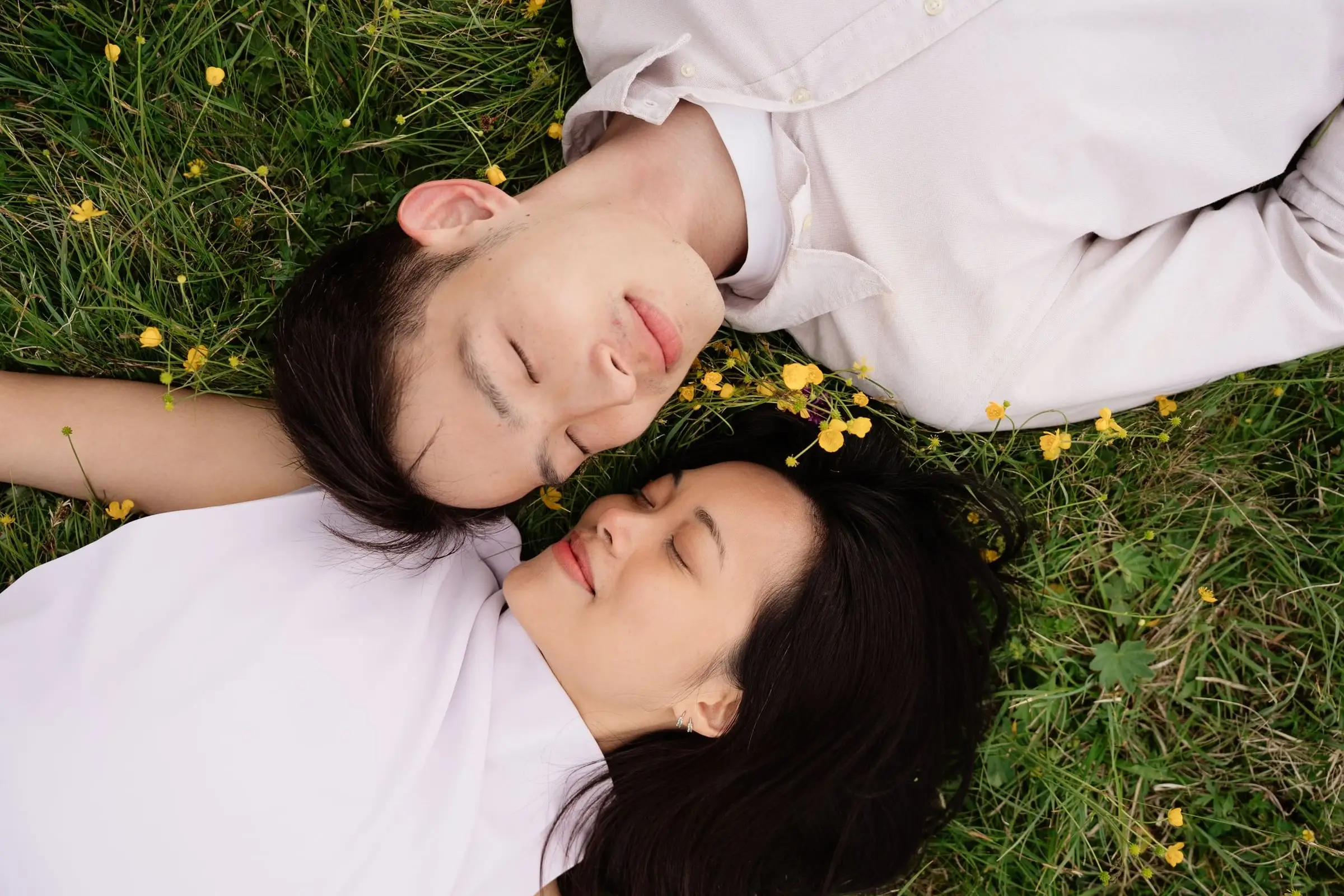 Couple lying head to head in the grass among yellow flowers