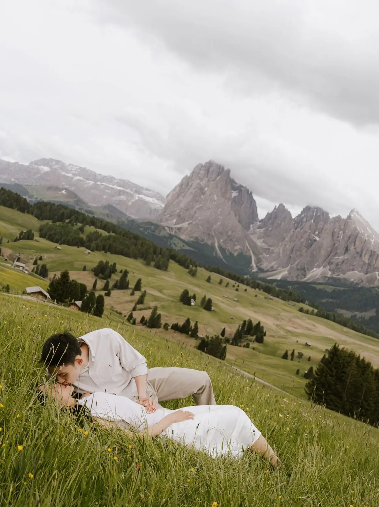 Couple lying in the meadow, the Sassolungo rising behind them