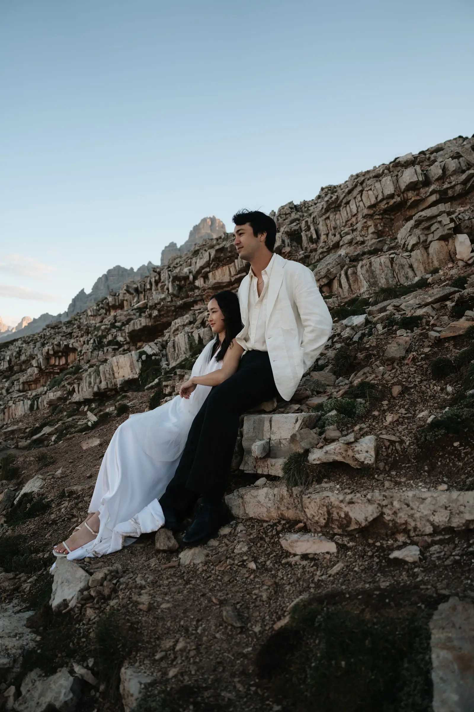 Couple sitting on the rocks of a mountain ridge in the Dolomites at blue hour