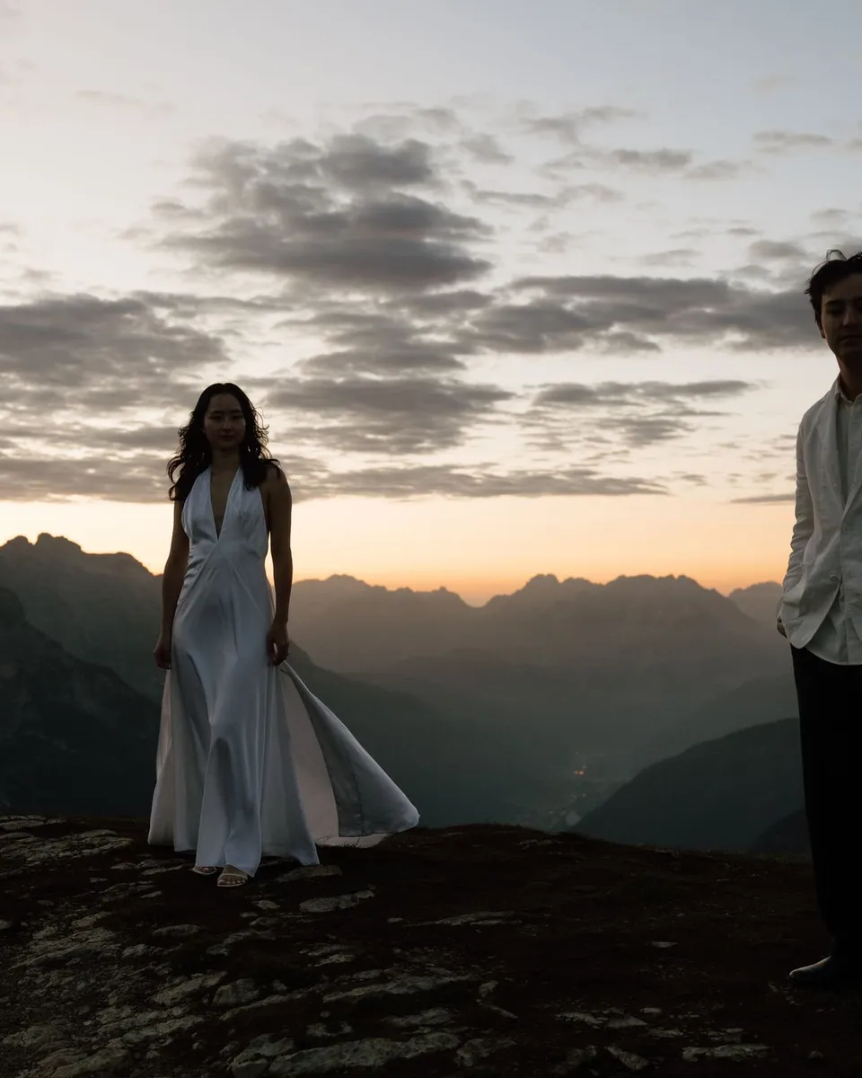 Silhouettes of the couple on the ridge as the sky glows orange before sunrise