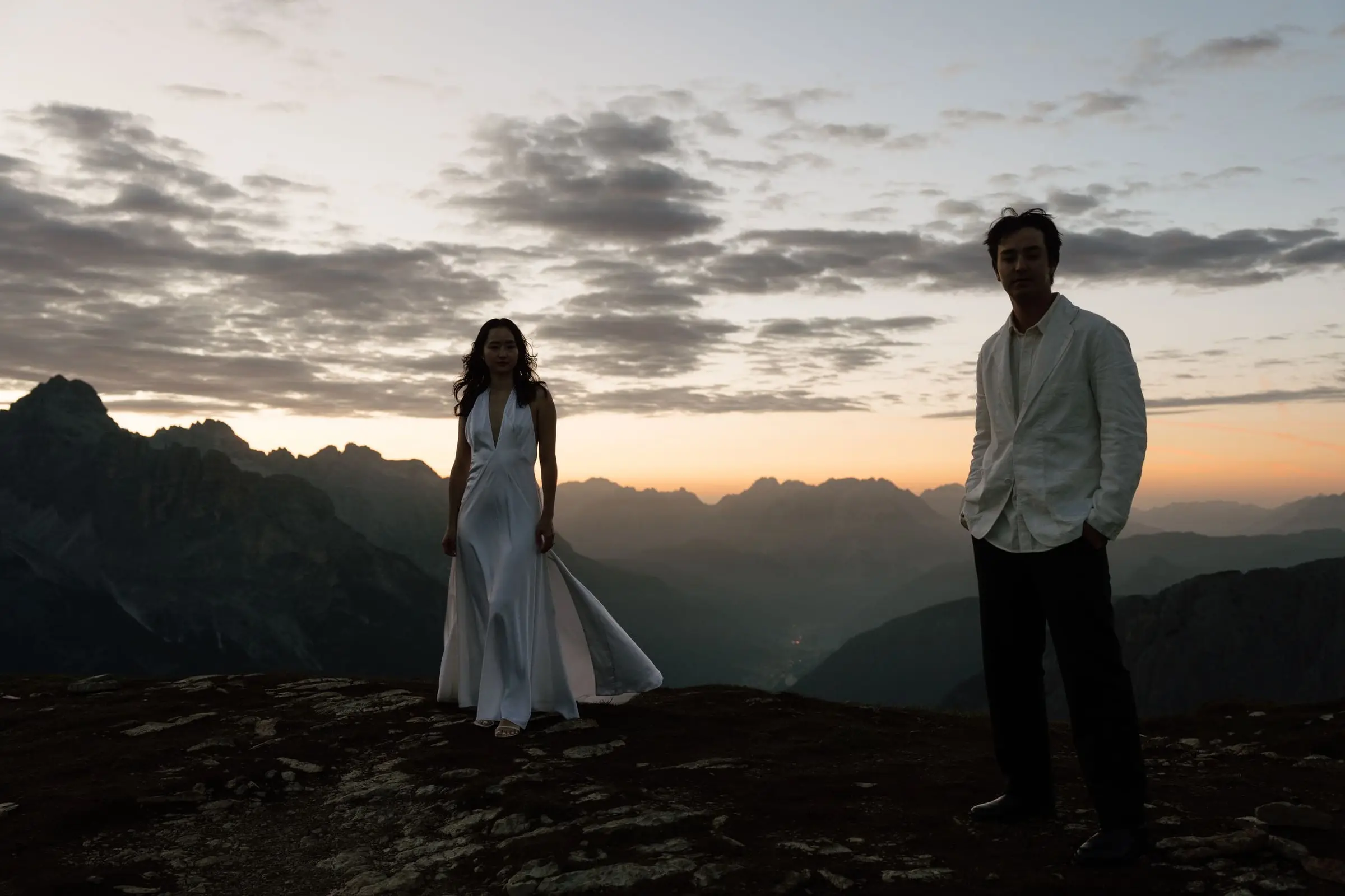 Silhouettes of the couple on the ridge as the sky glows orange before sunrise