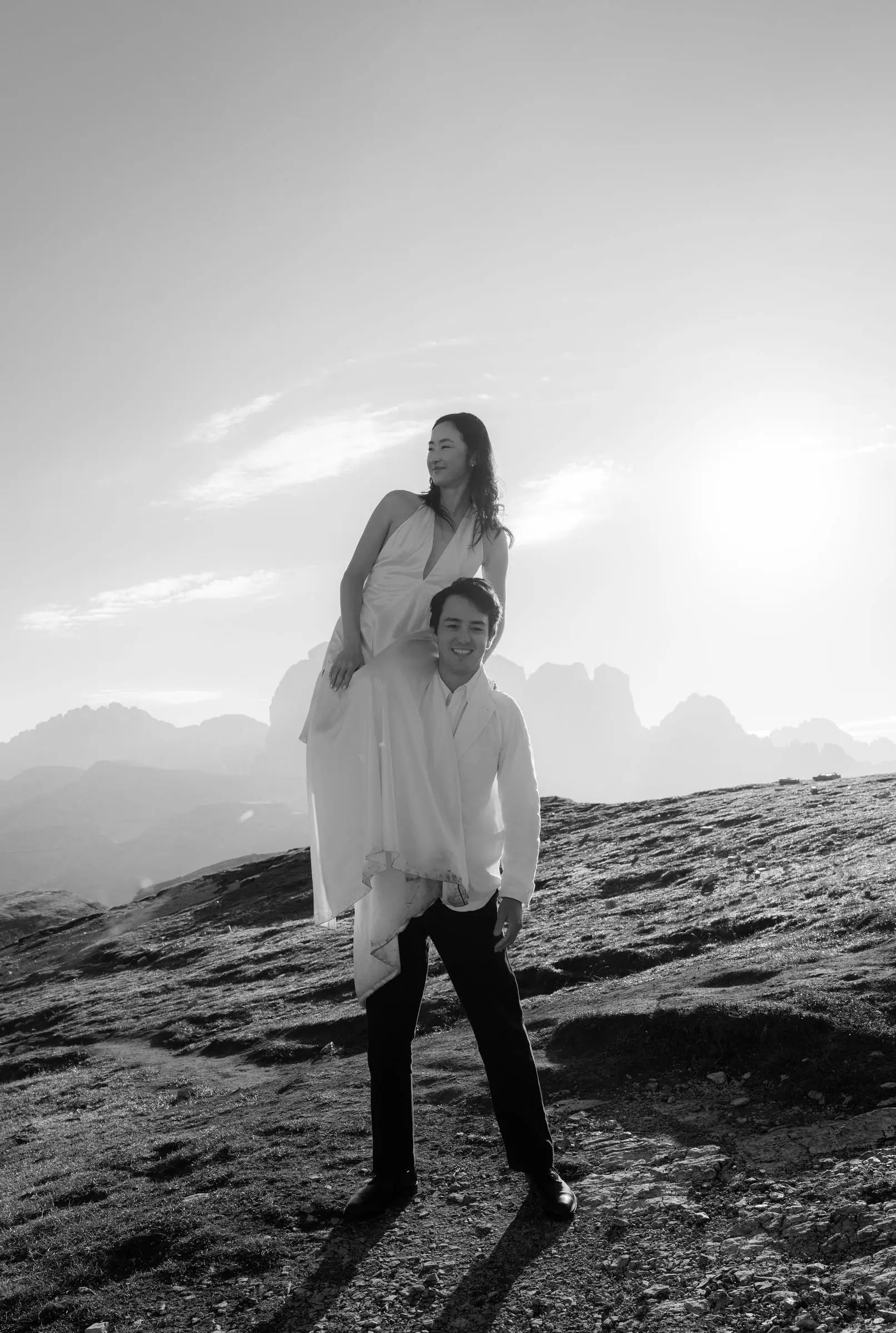 Black and white photo of the groom carrying the bride on his shoulders