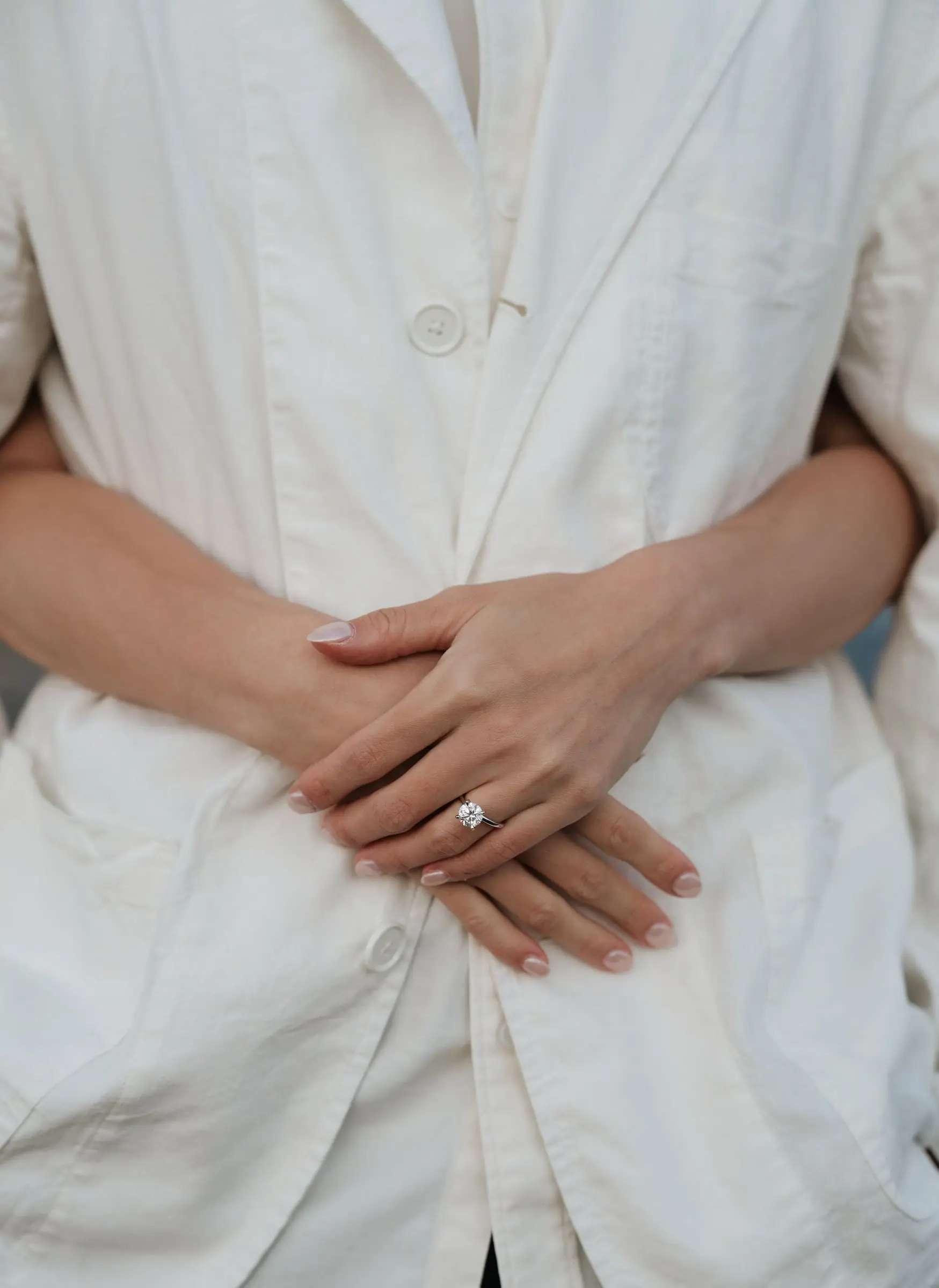 Close-up of her hands with an engagement ring holding his white jacket