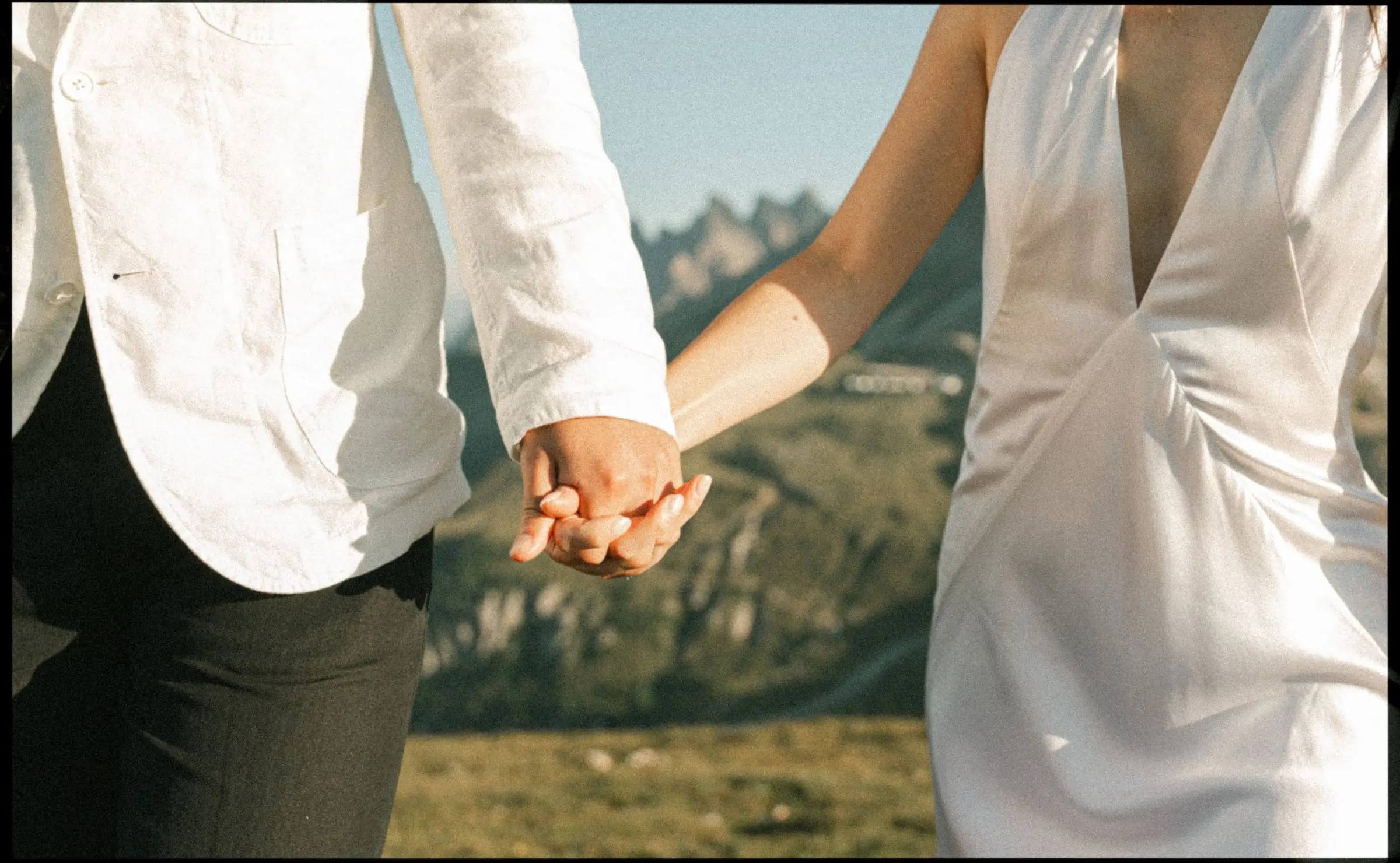 Close-up of the couple holding hands against the mountains, on film