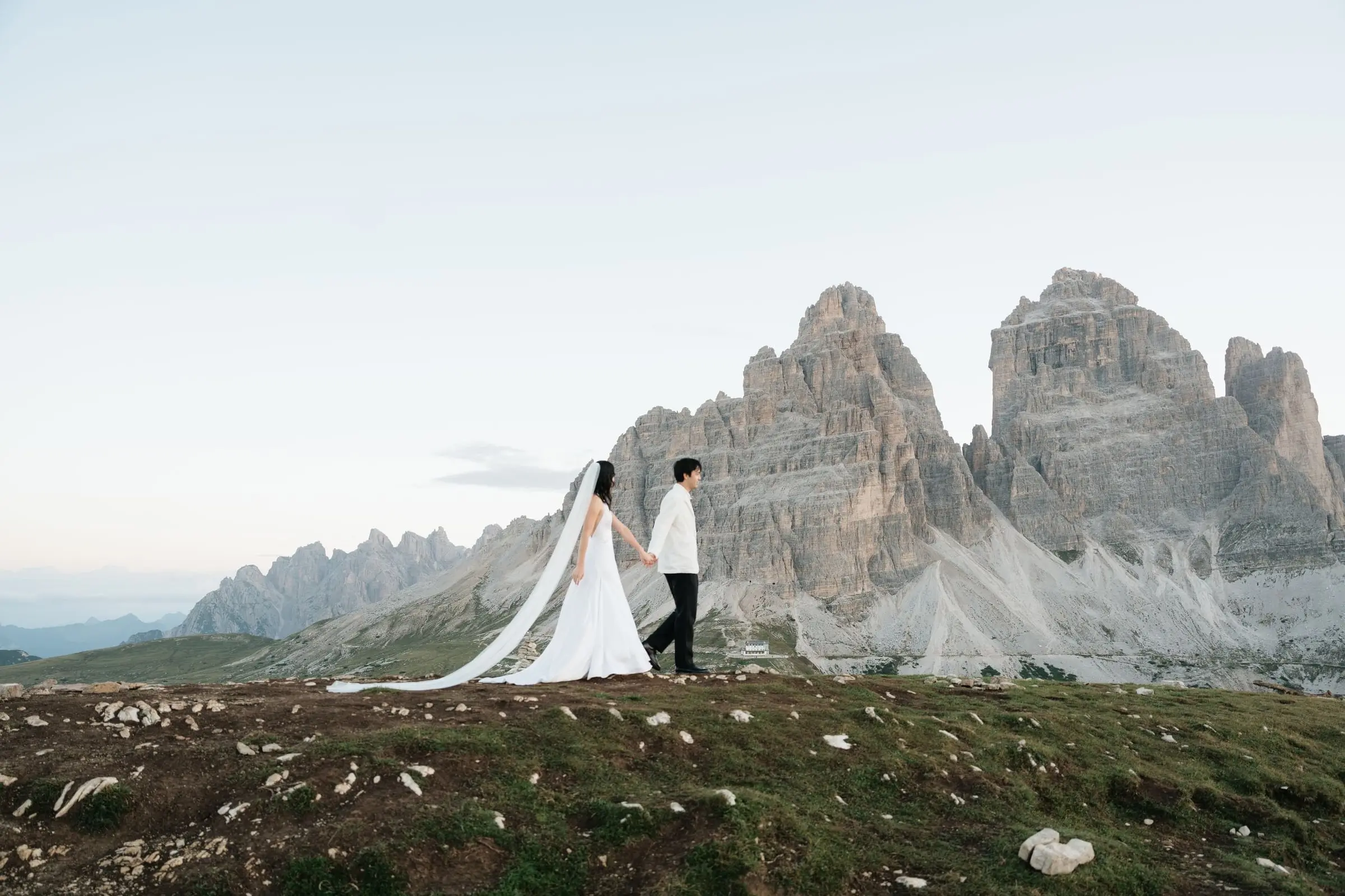 Couple walking with a long veil in front of the Tre Cime di Lavaredo