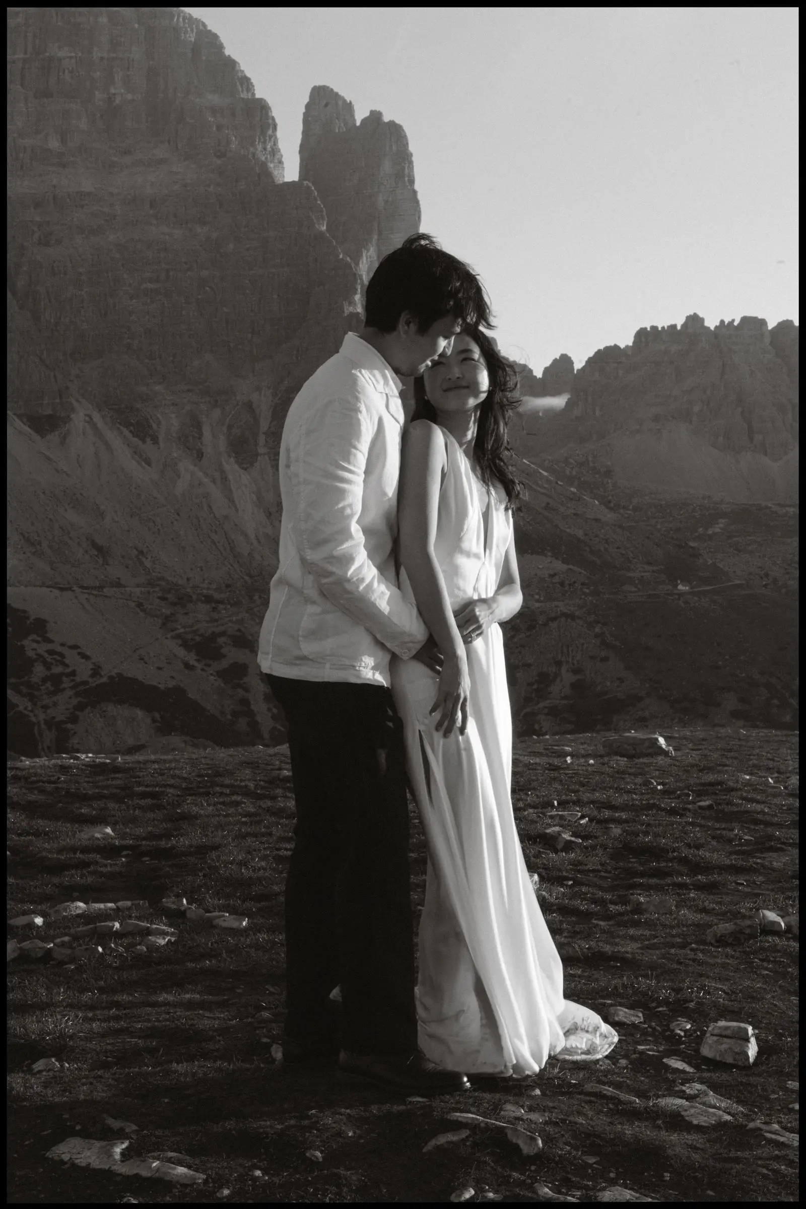 Black and white photo of the couple close together below the Dolomites peaks