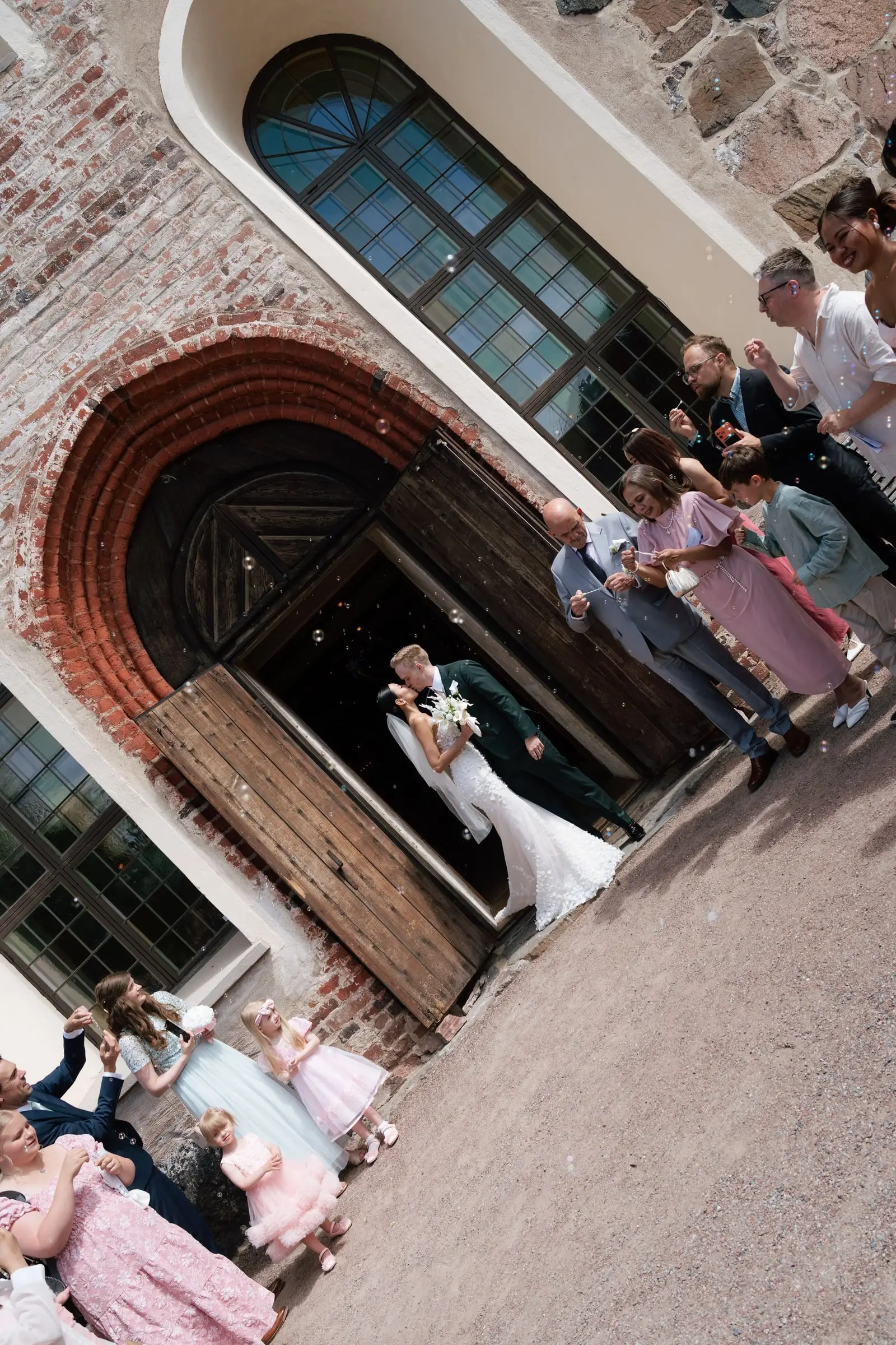 Newlyweds kissing in the church doorway as guests throw confetti