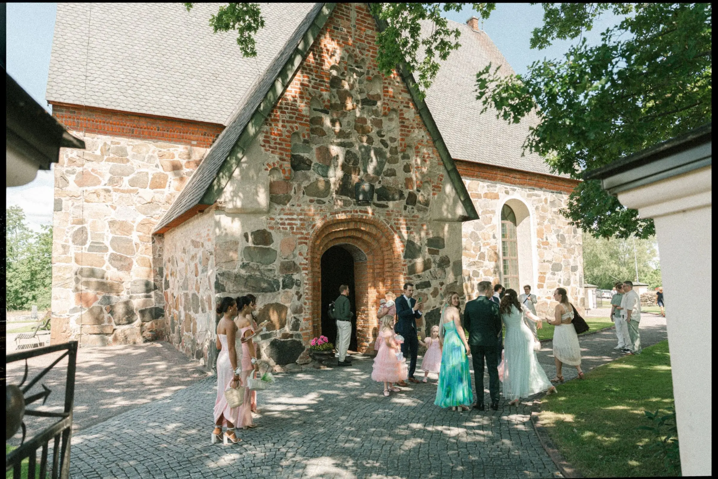 Guests gathering outside the medieval stone church near Falun, on film