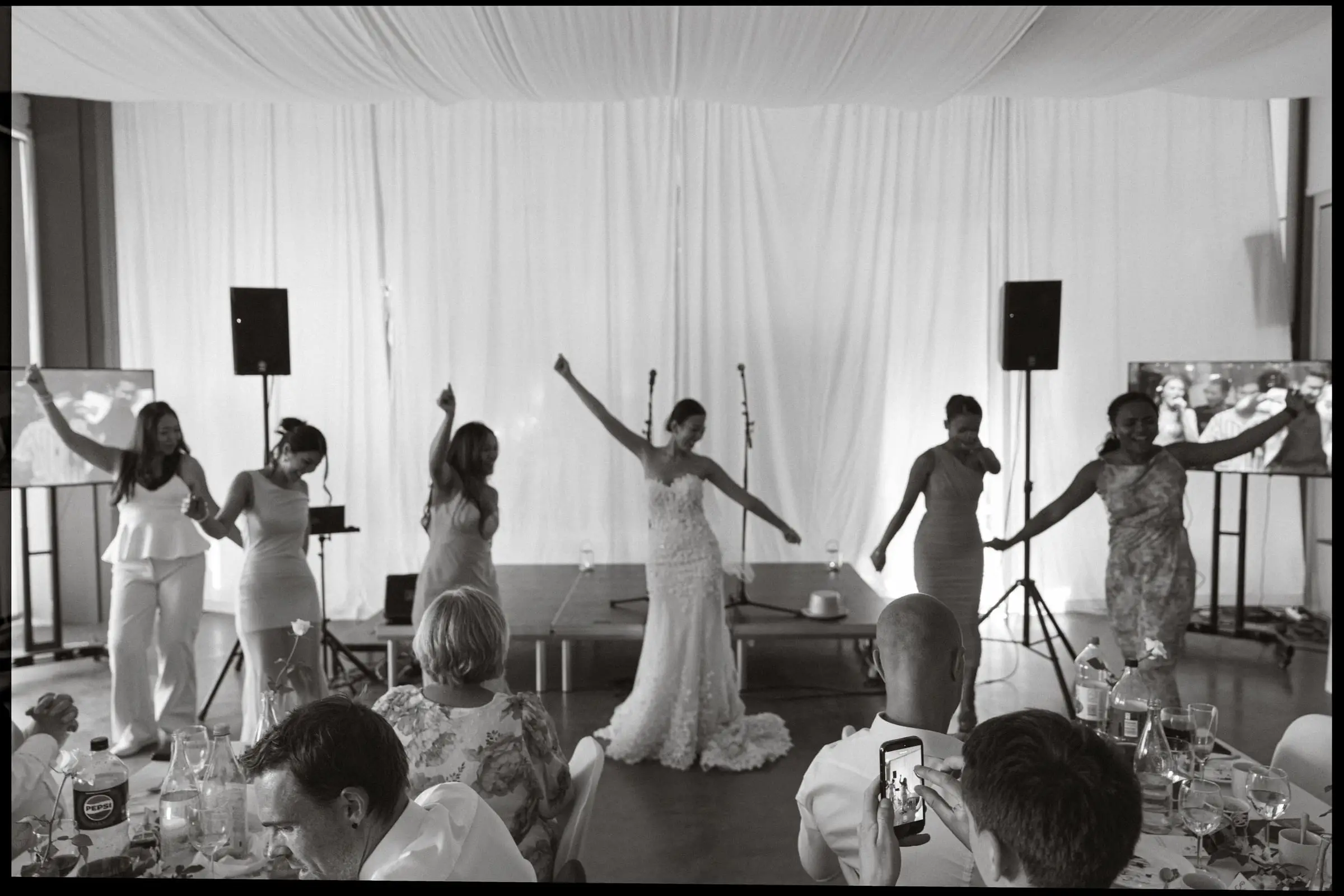 Black and white photo of the bride dancing with her bridesmaids at the reception