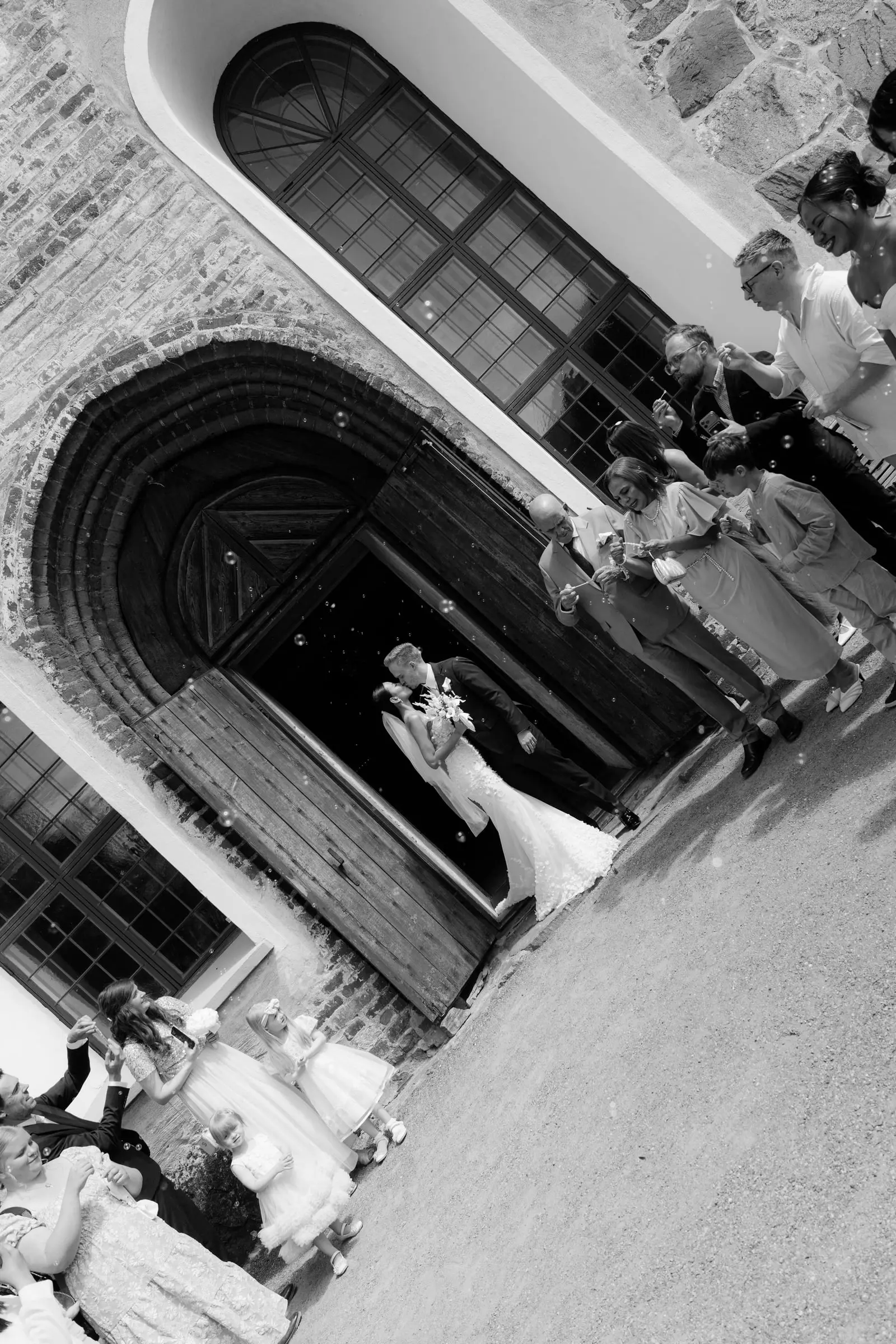 Black and white photo of the couple kissing in the church doorway
