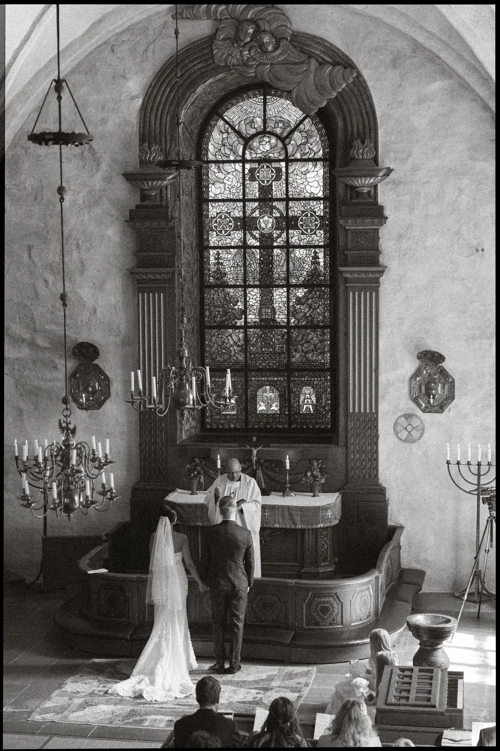 Black and white photo of the couple at the altar of the old church, on film