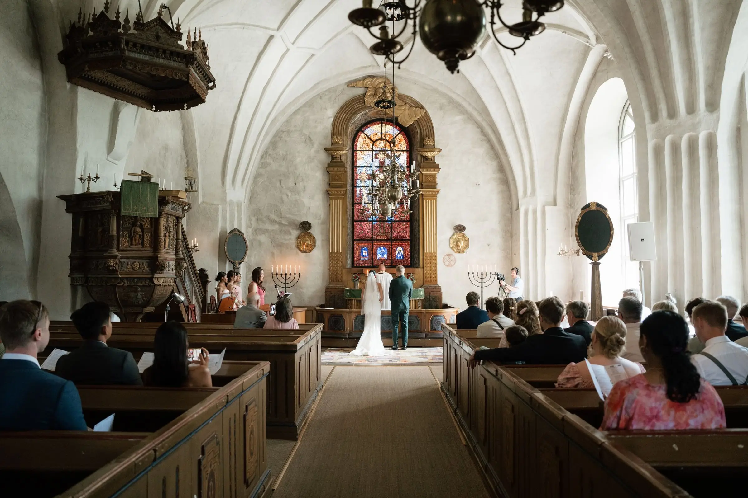 Wedding ceremony in the white-vaulted Swedish church, guests in the pews