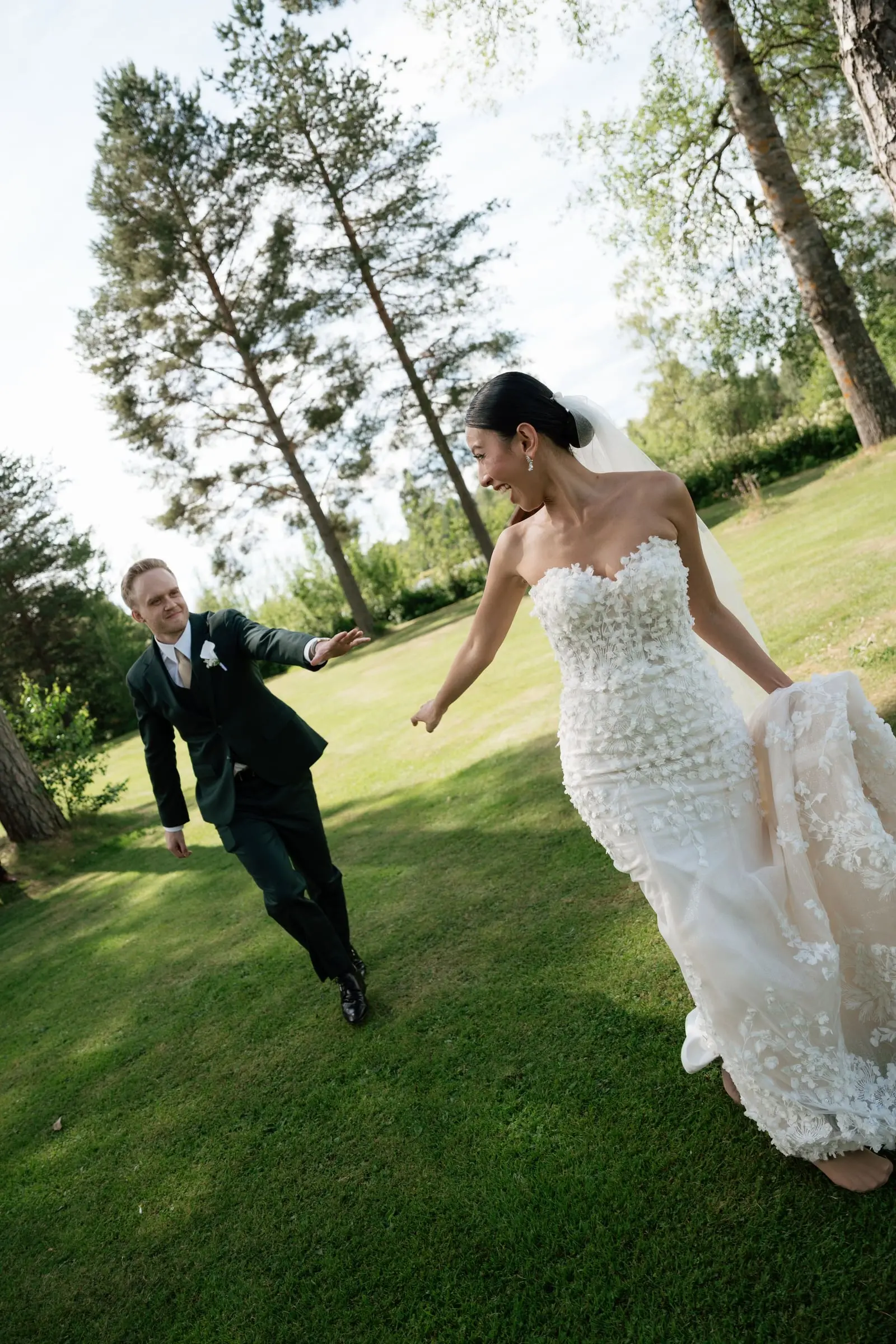 Groom runs after the bride across the lawn, holding her hand