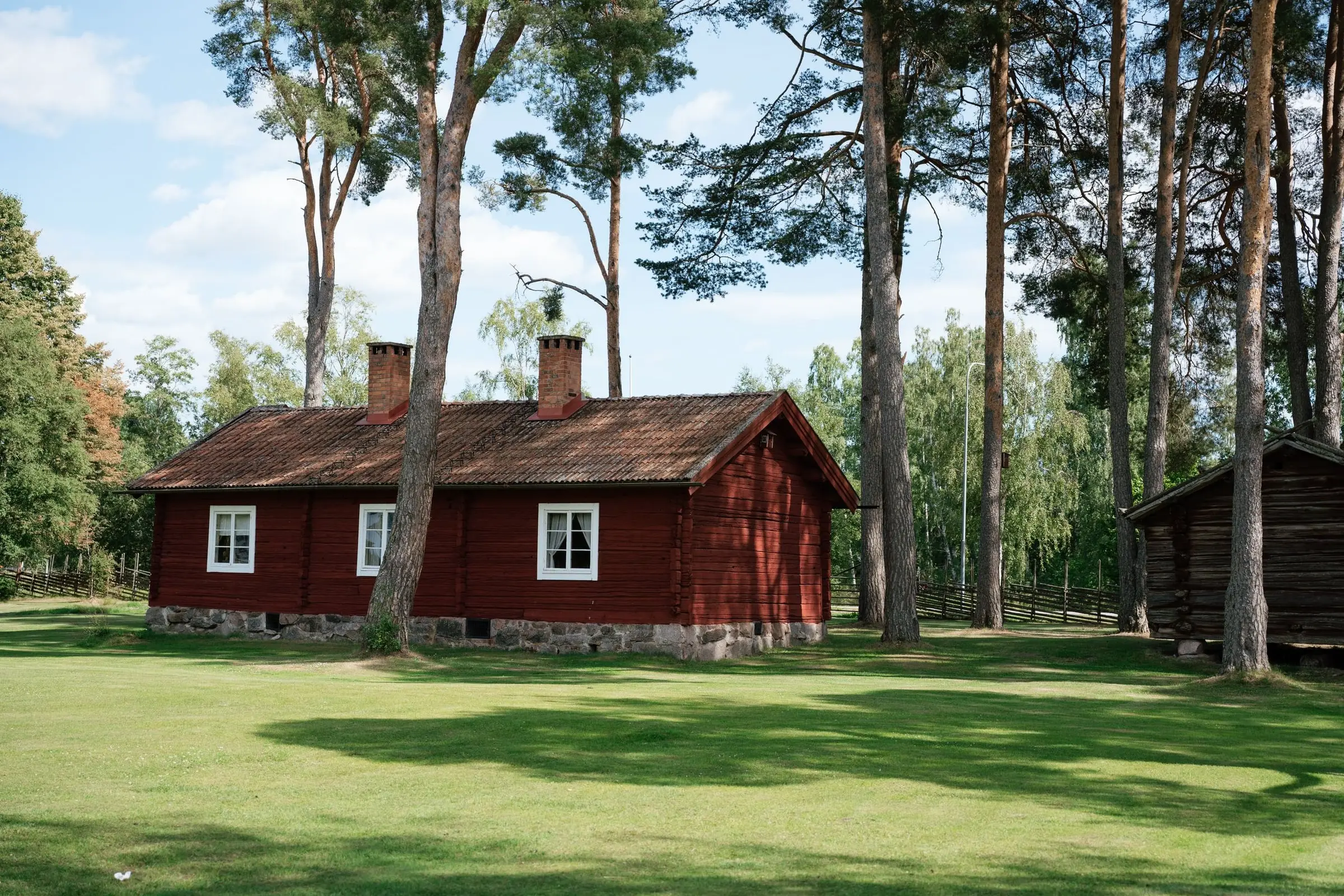 A traditional red wooden house among pine trees in Dalarna
