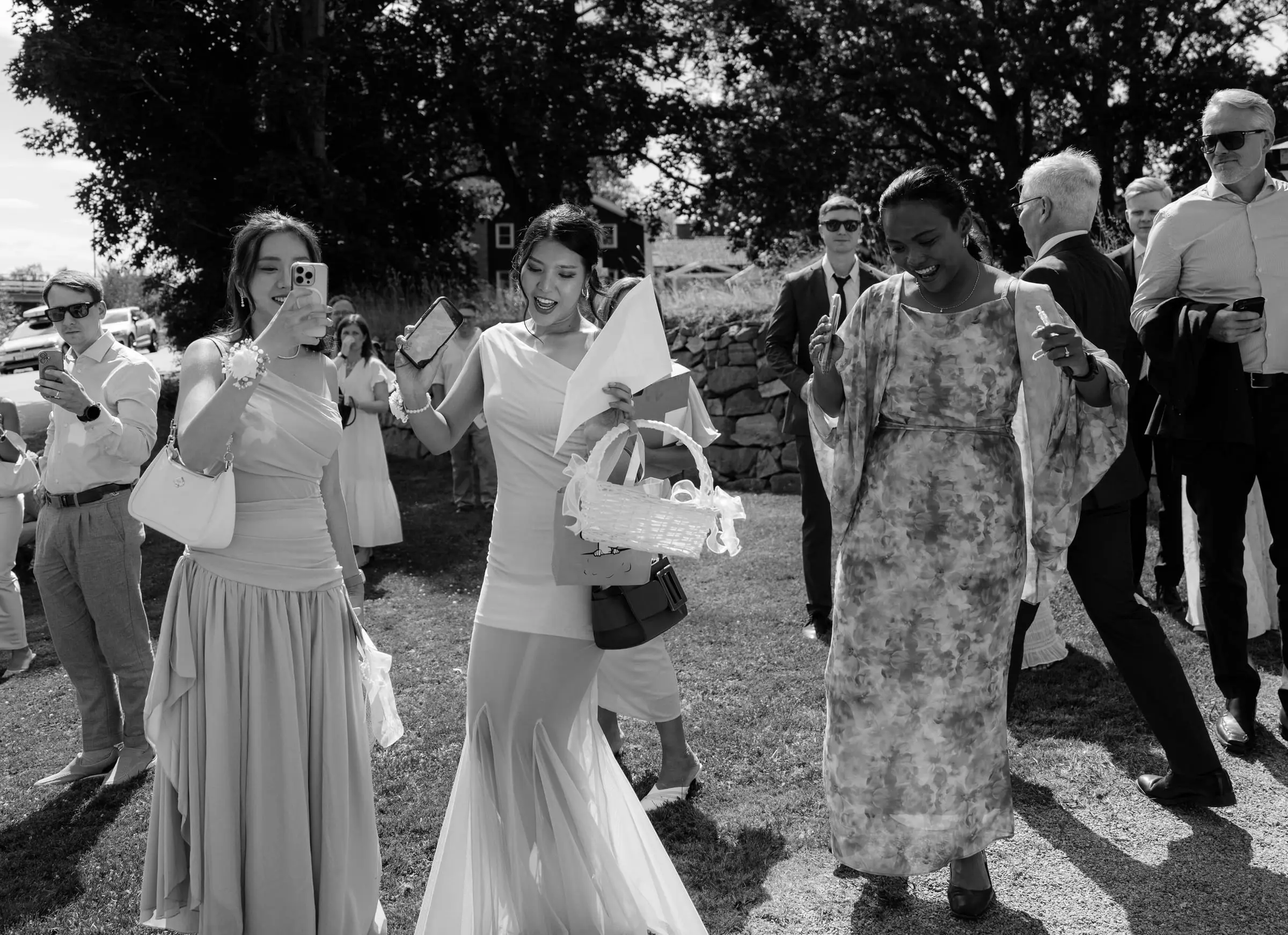 Black and white photo of guests throwing petals and filming the couple