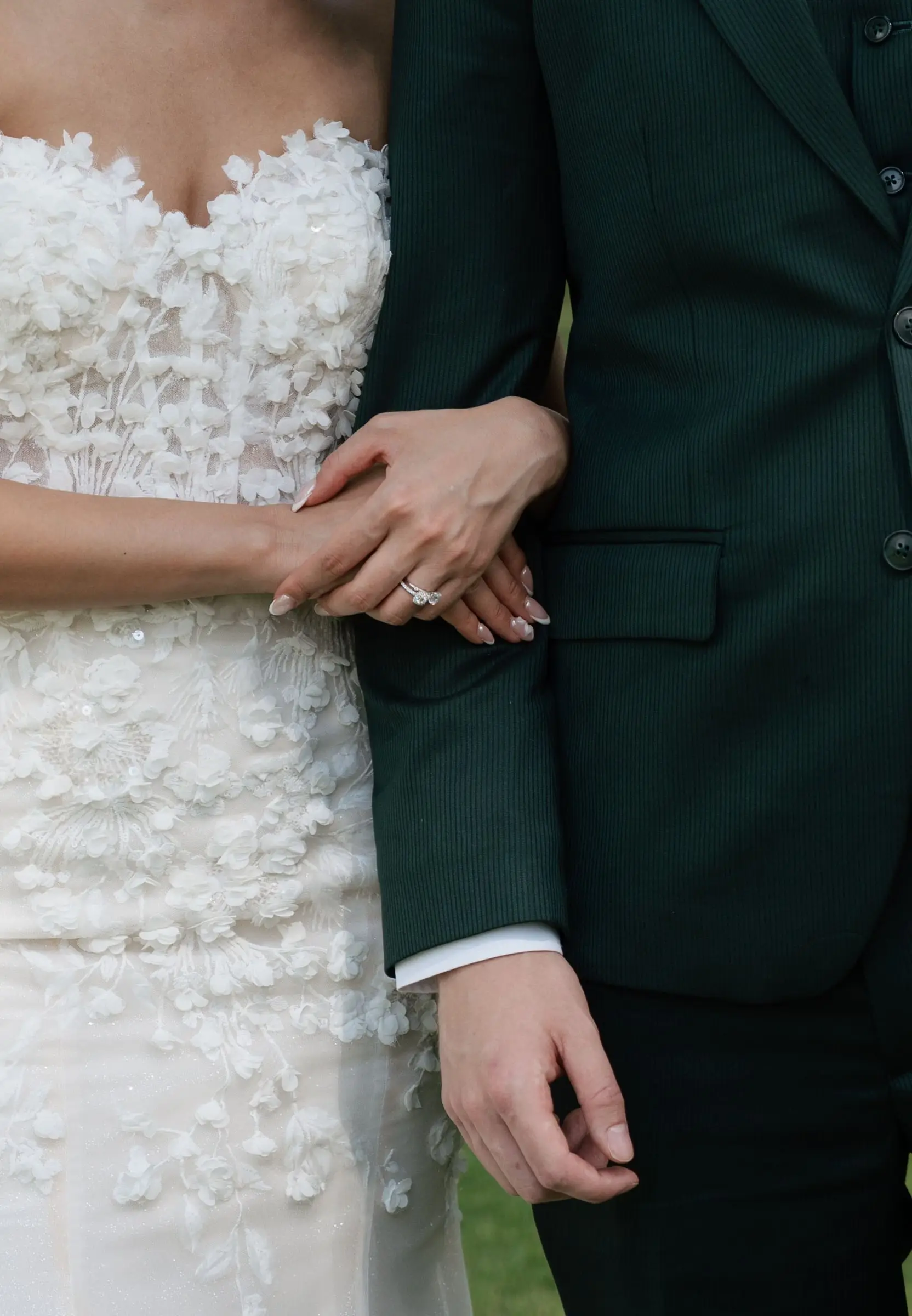 Close-up of the bride's hand with rings resting on the groom's arm