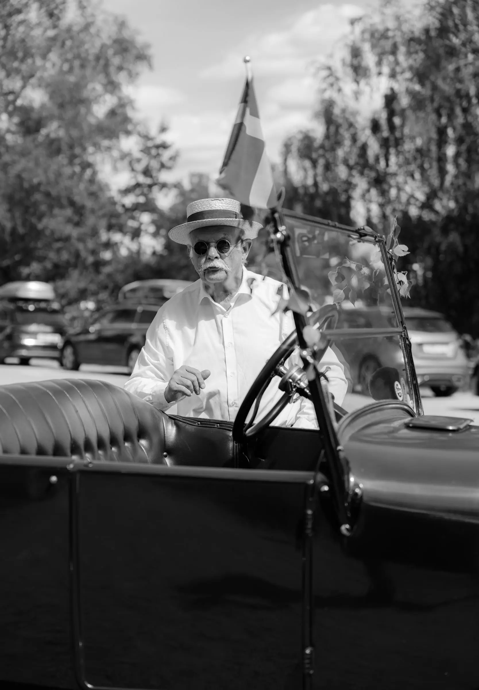 Black and white photo of the driver at the wheel of the vintage car