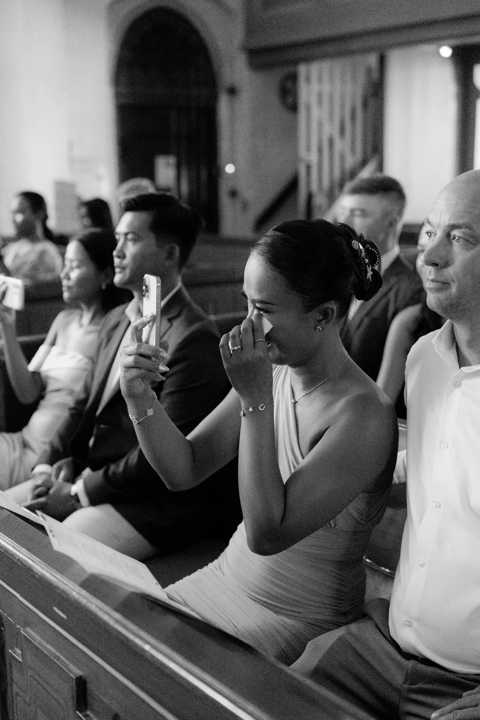 Black and white photo of a guest wiping away tears in the pews
