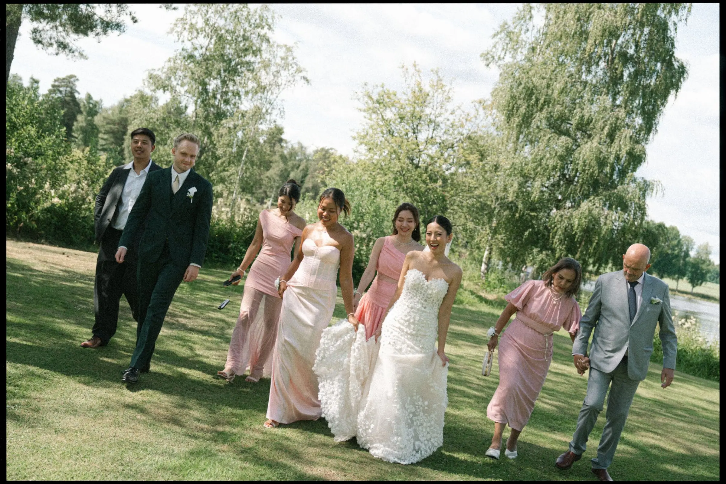 Wedding party walking across the lawn, bridesmaids in pink, on film