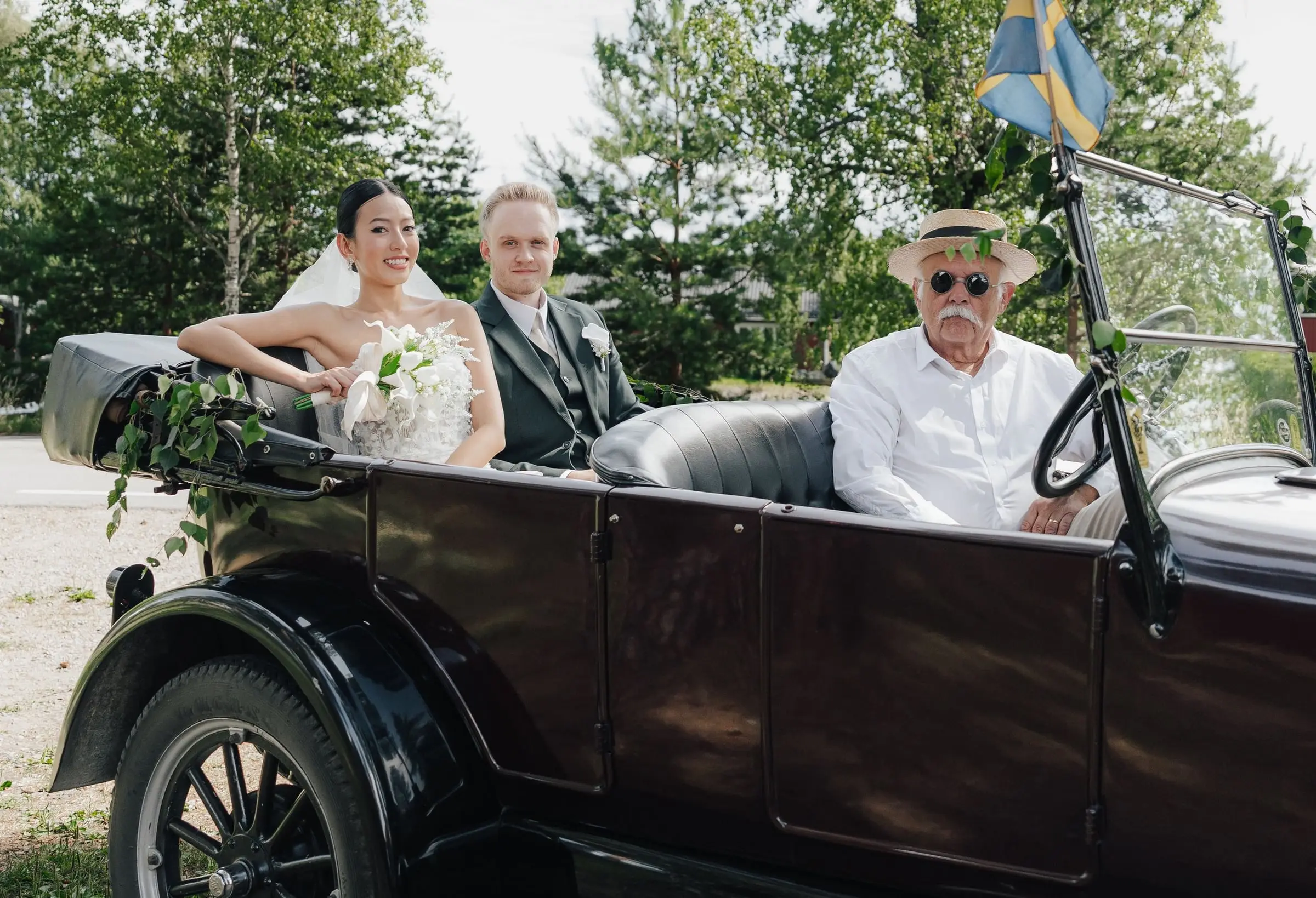 Newlyweds in the back of a vintage car with the driver