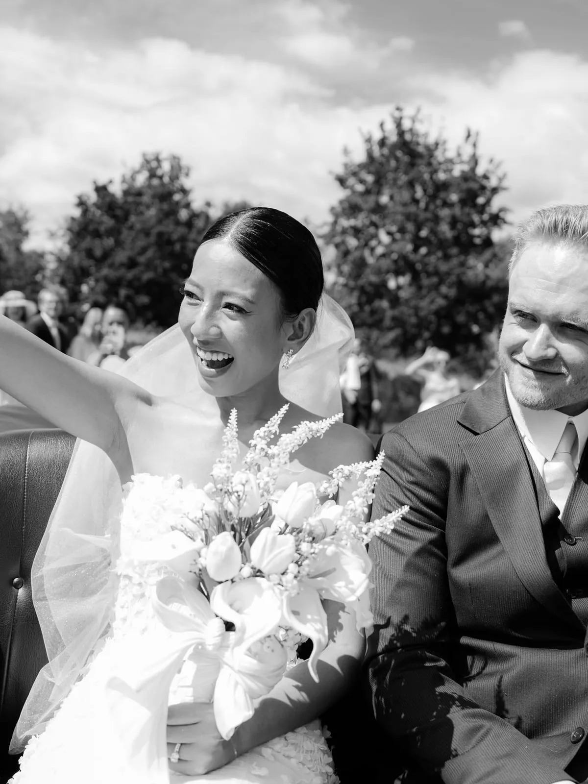 Black and white photo of the bride waving from the car