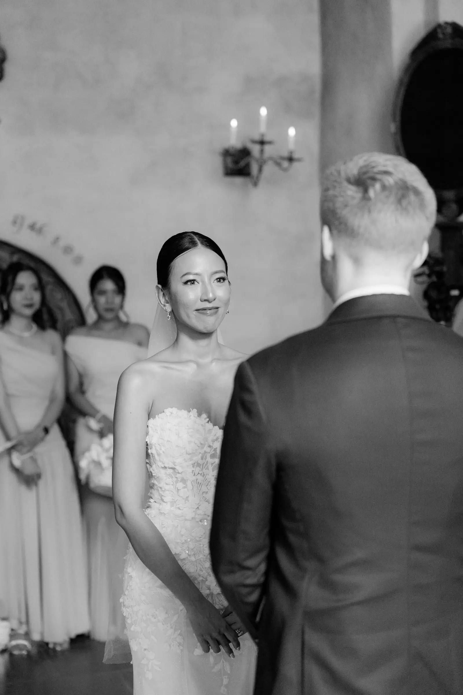 Black and white photo of the bride smiling at the groom during the ceremony