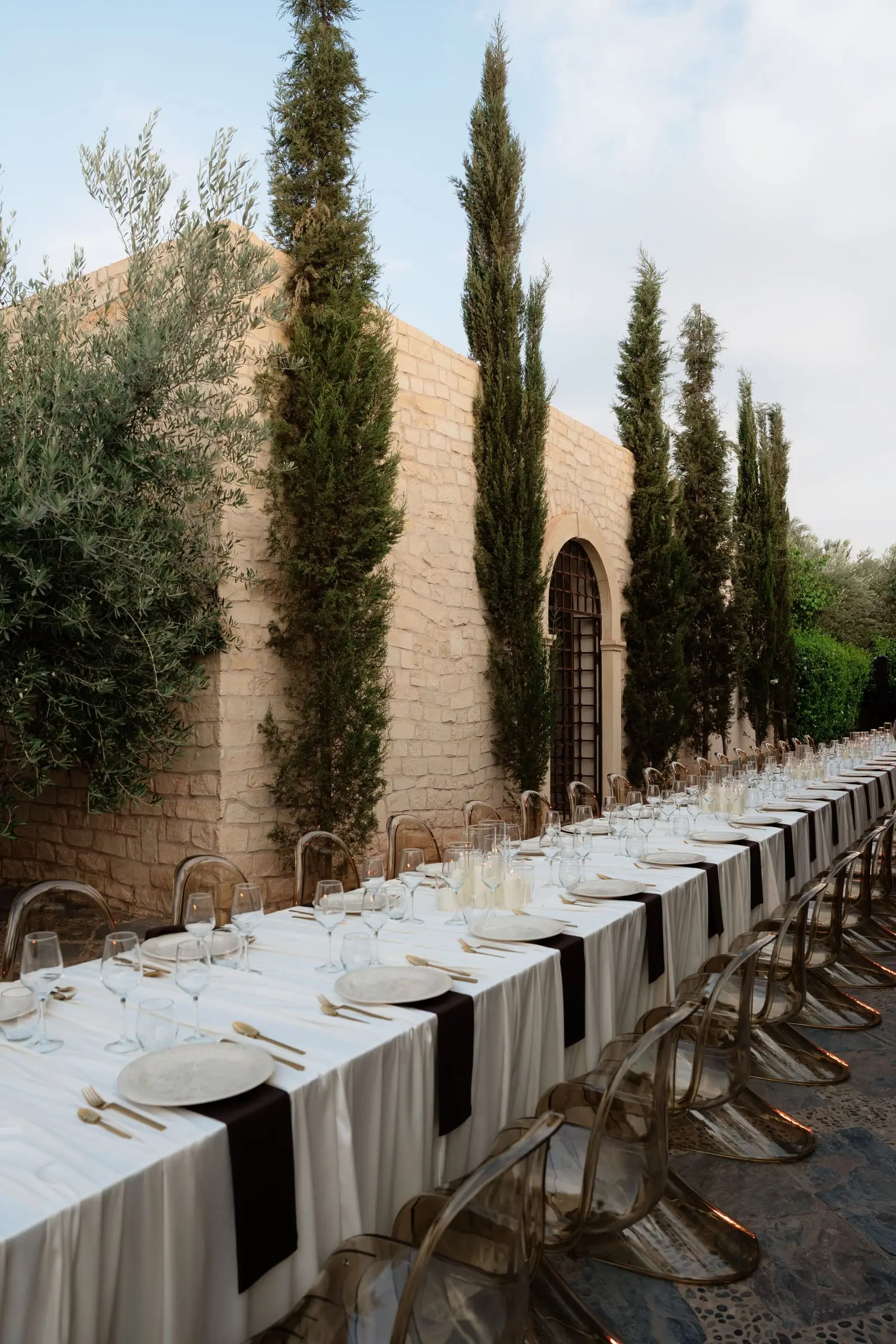 Long dinner table set between cypress trees at Ksar Char Bagh in Marrakech