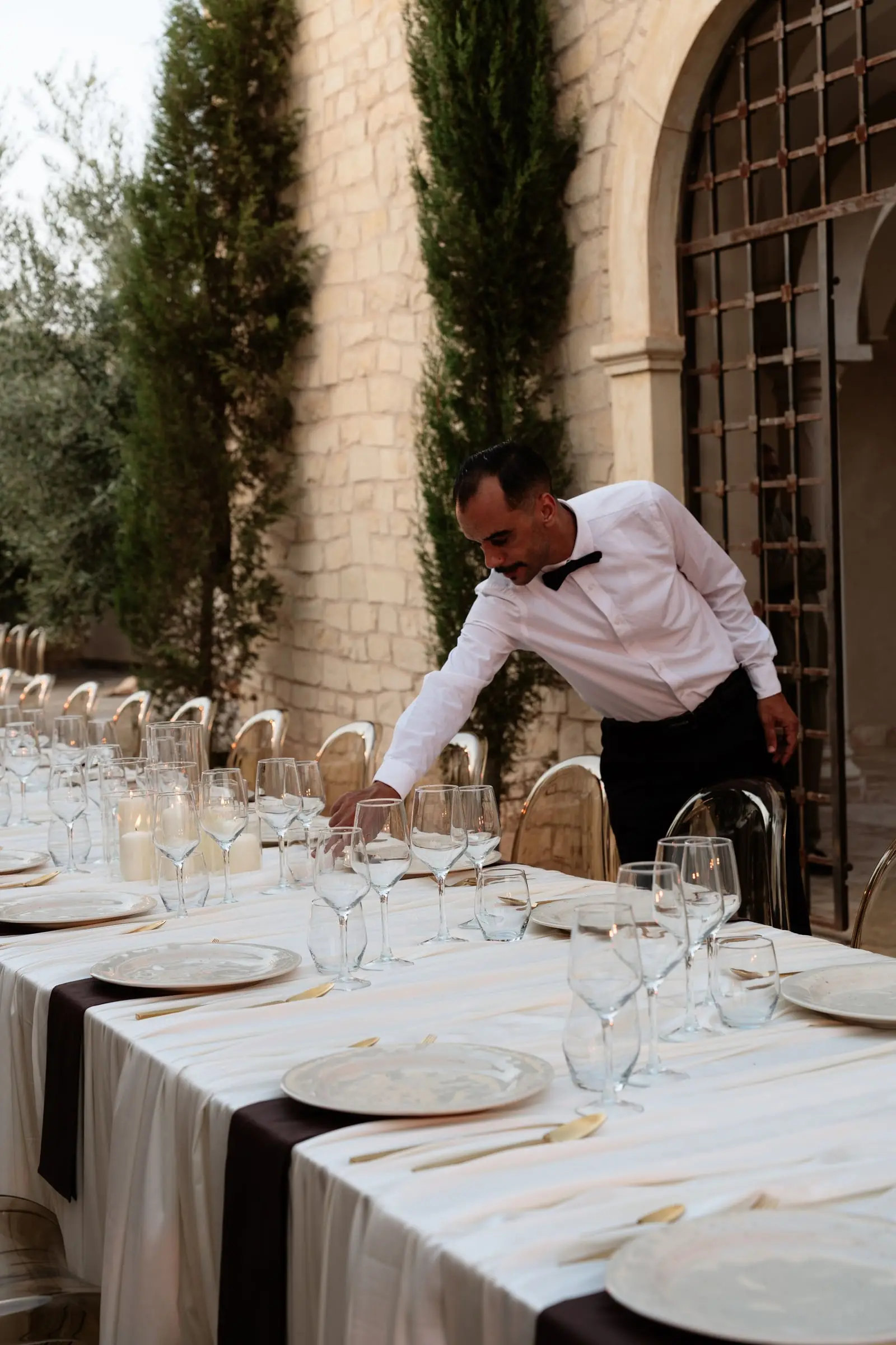 Waiter setting the welcome dinner table beside the palace walls