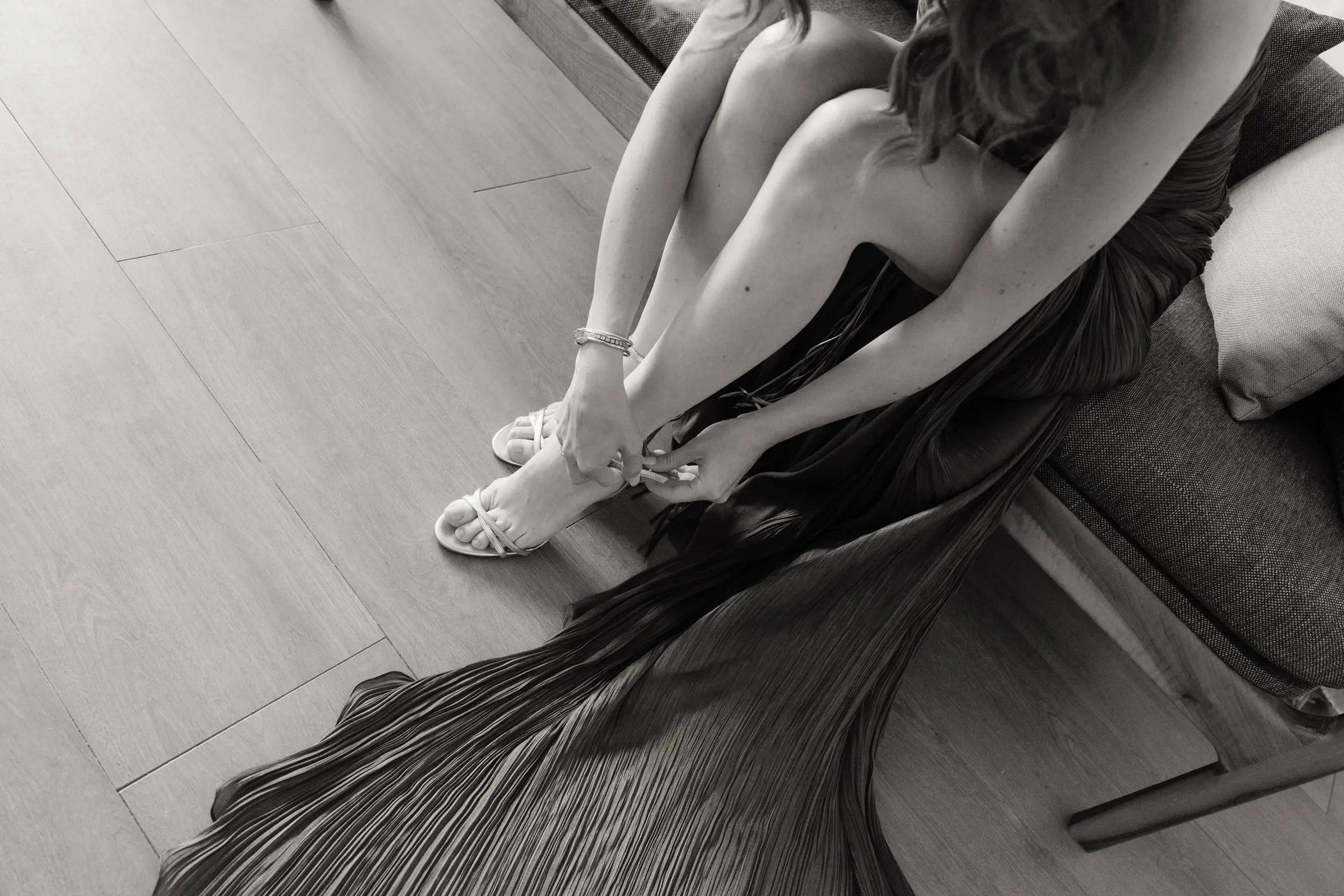 Black and white photo of the bride fastening her sandals