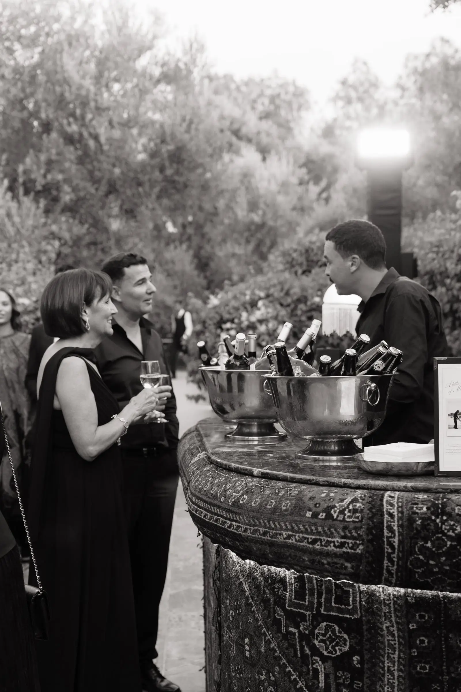 Black and white photo of guests at the drinks bar in the garden