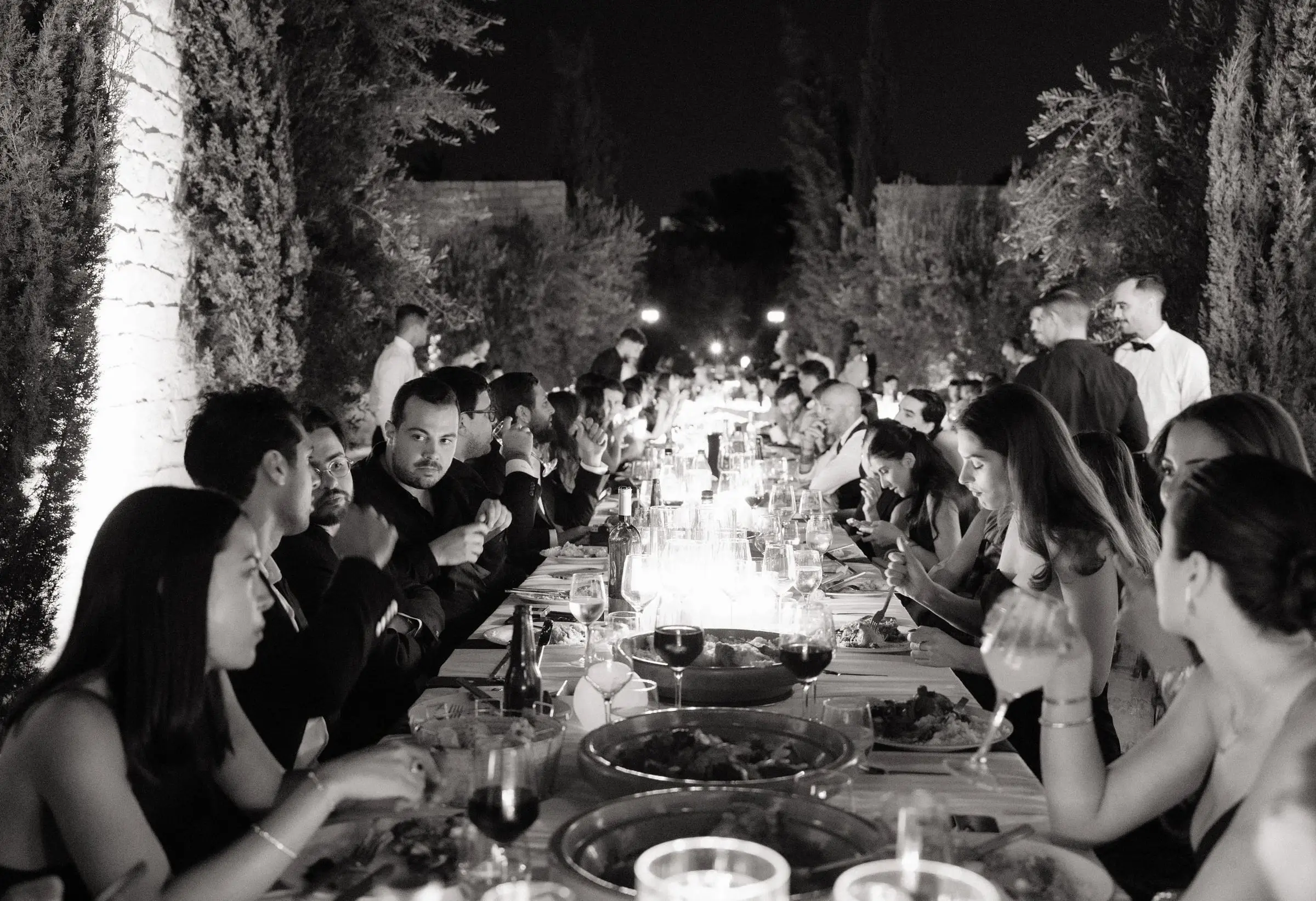 Black and white photo of guests along the long dinner table