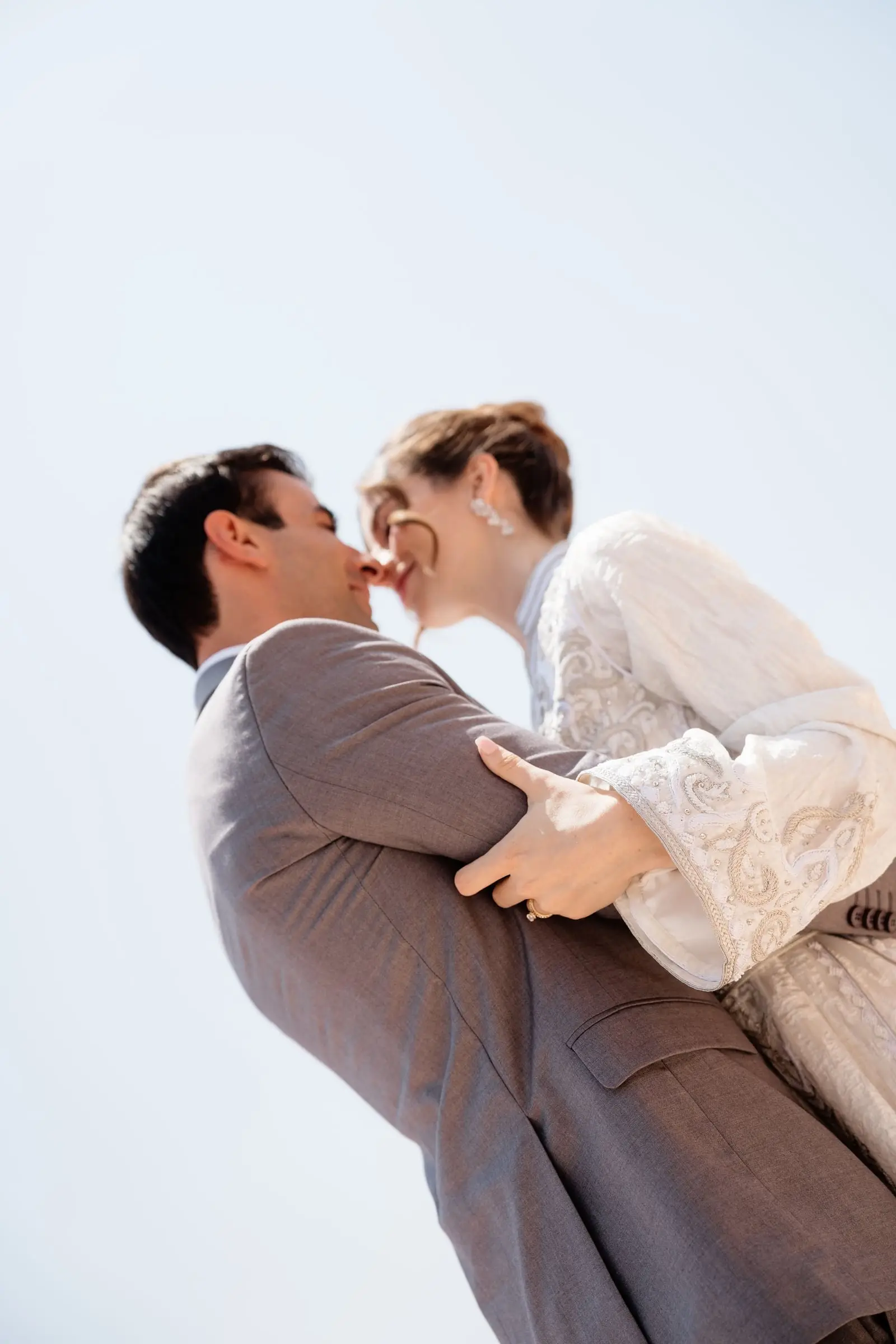 Groom lifts the bride against the blue Marrakech sky