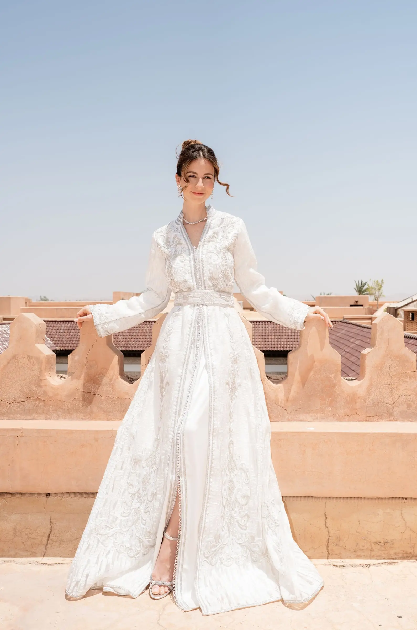 Bride in an embroidered white kaftan on the crenellated rooftop