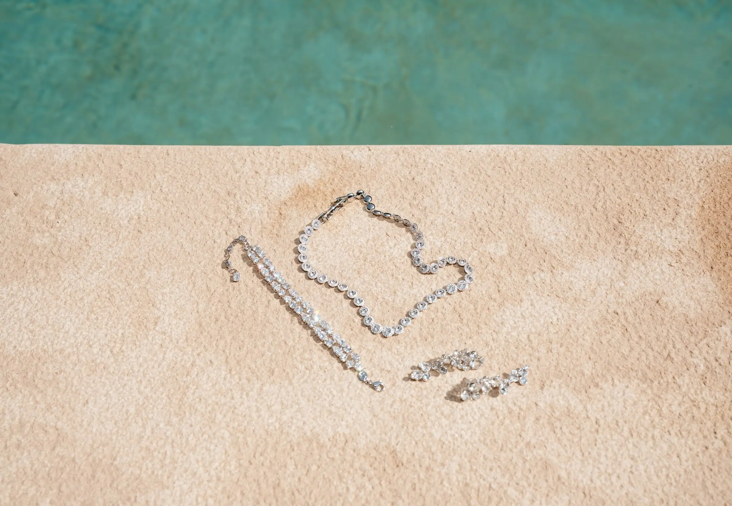 Bridal jewellery laid out beside a turquoise pool