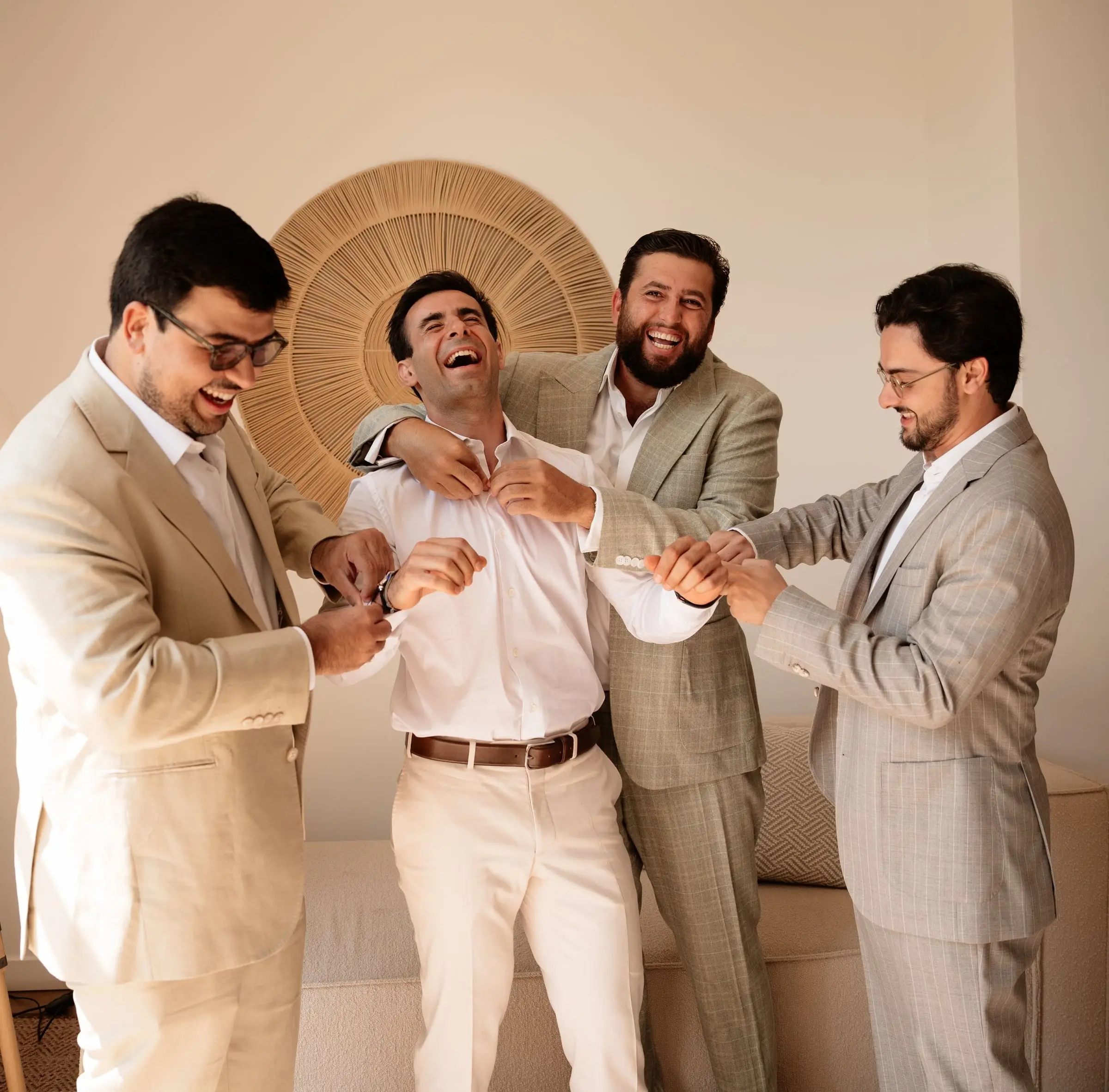 Groomsmen helping the laughing groom get dressed
