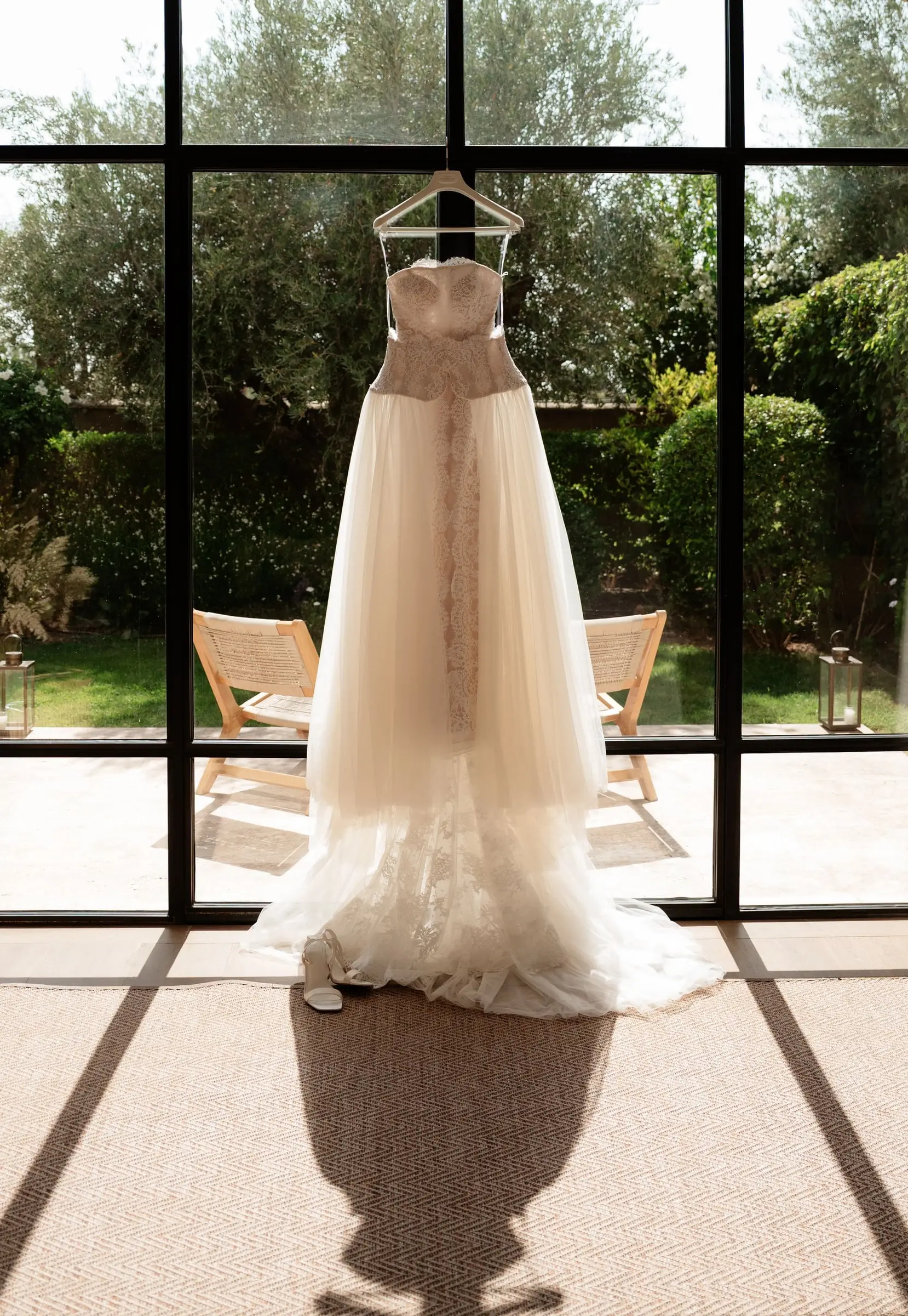 Wedding dress hanging in front of a tall garden window